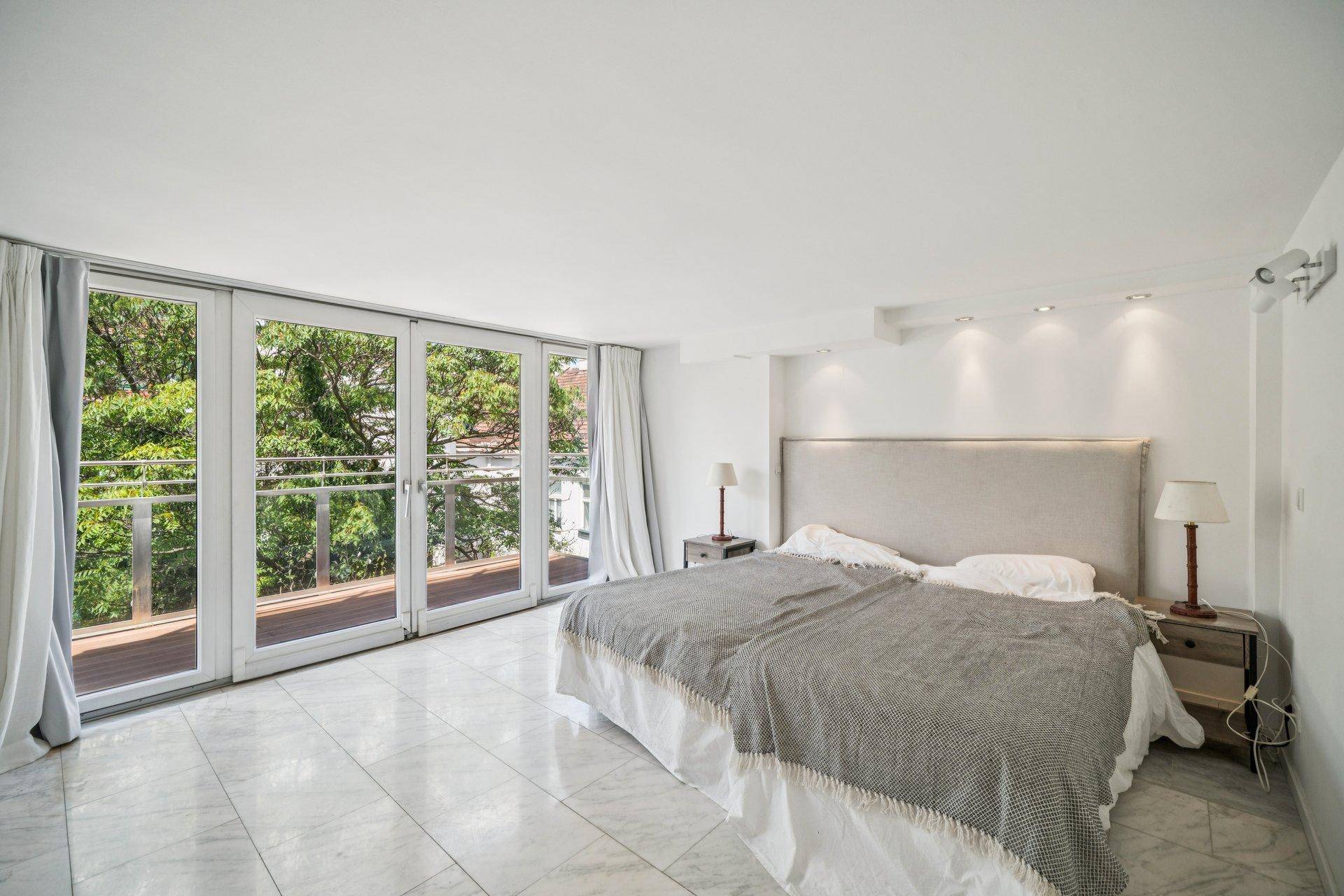 Helles Schlafzimmer mit großzügigen Fenstern, Balkonzugang und einem schönen Blick ins Grüne.