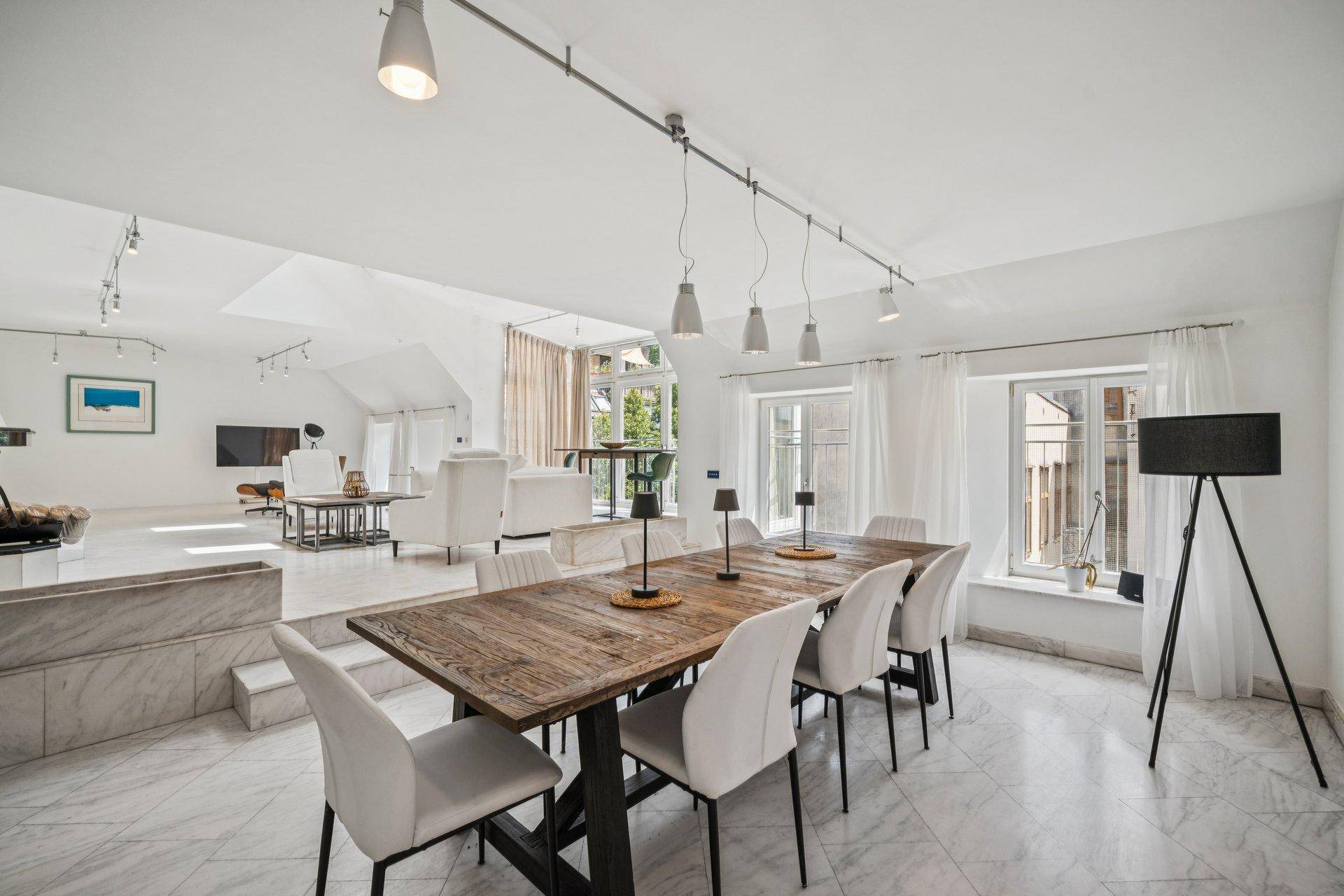 Geräumiger Essbereich mit Holztisch, modernen Stühlen und Marmorboden, verbunden mit dem Wohnzimmer.