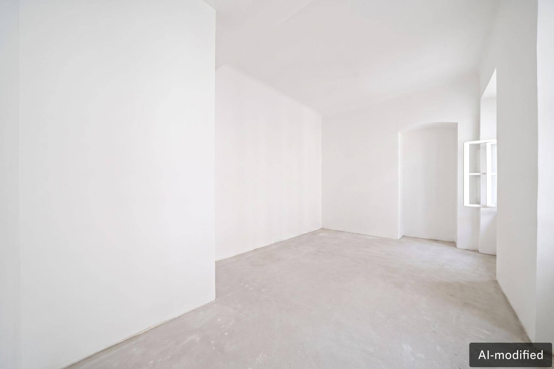 Heller Raum mit Betonboden und einem kleinen Fenster, geeignet als Schlaf- oder Arbeitszimmer.