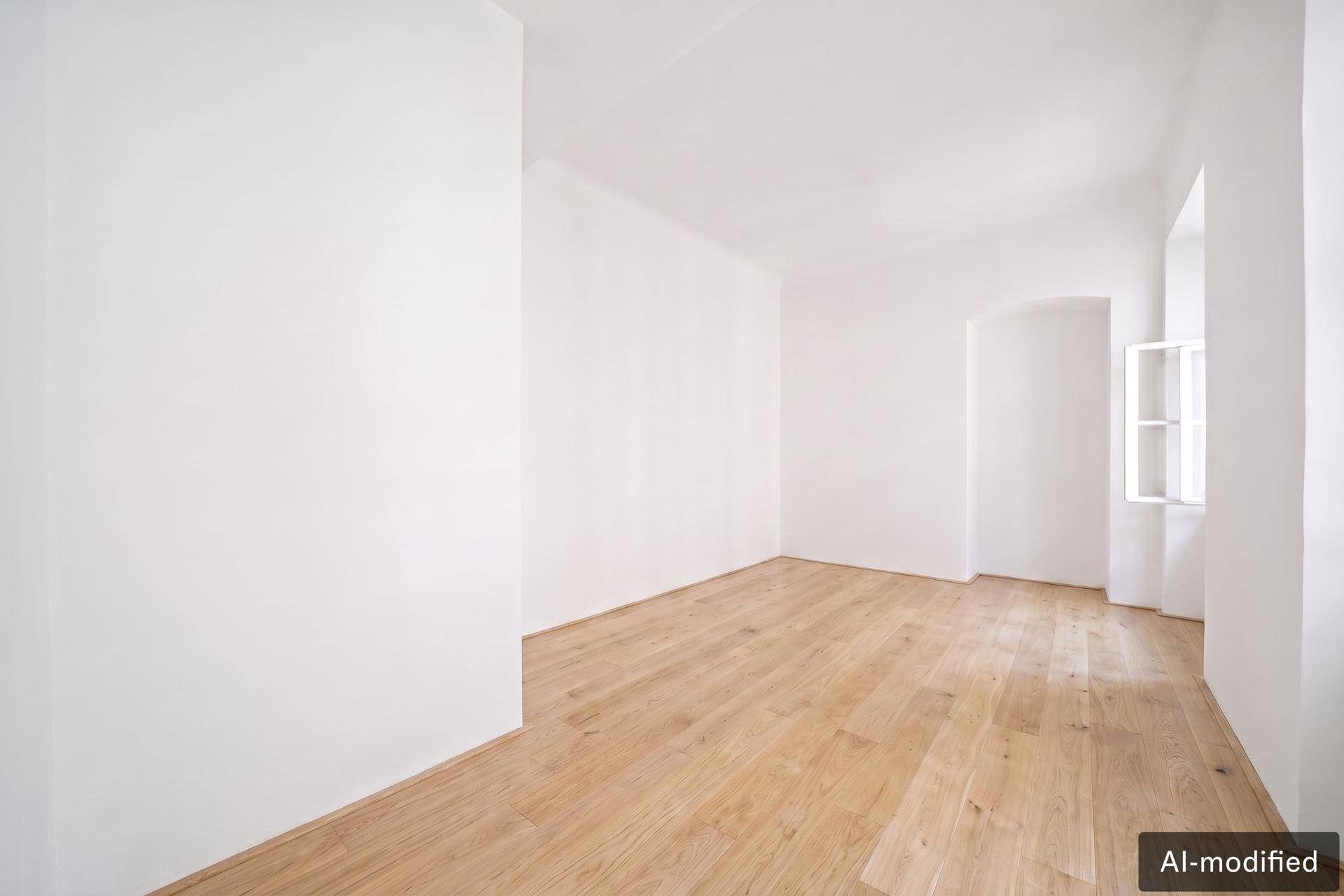 Heller Raum mit Holzdielenboden und einem kleinen Fenster, ideal als Schlaf- oder Arbeitszimmer.