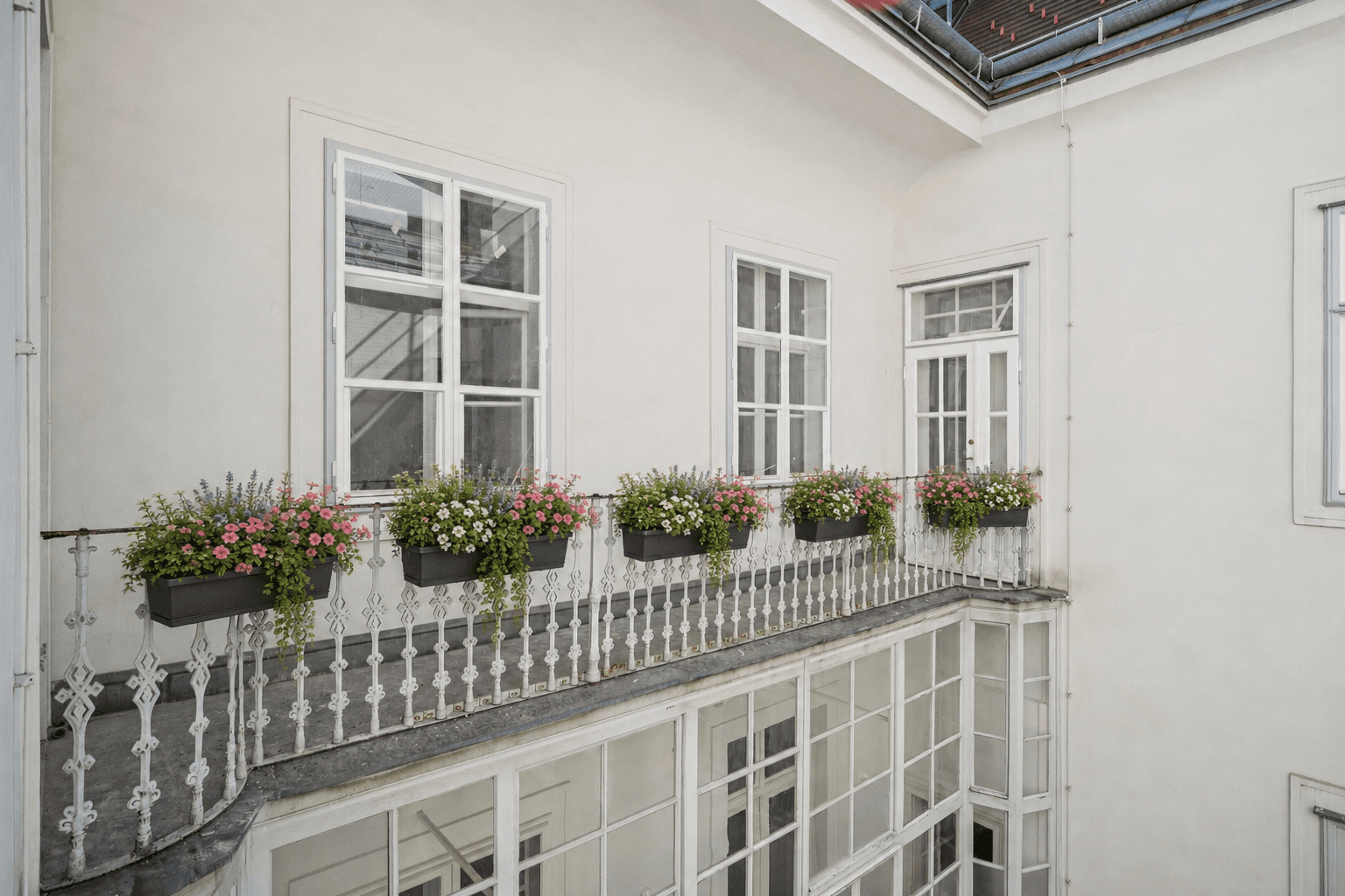 Historischer Balkon mit schmiedeeisernem Geländer und Blumenkästen mit Blick auf den Innenhof.