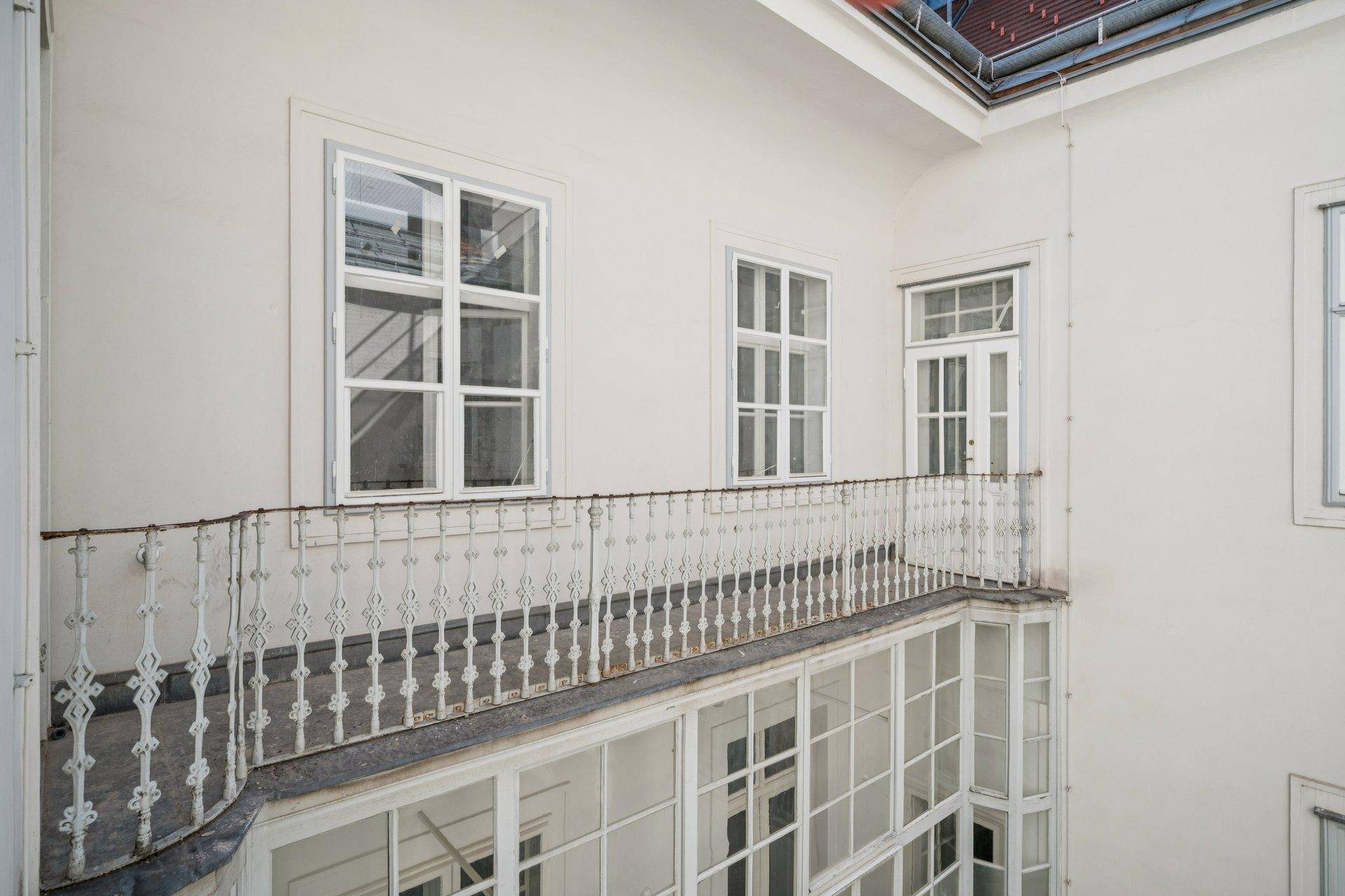 Historischer Balkon mit schmiedeeisernem Geländer und Blick auf den ruhigen Innenhof.