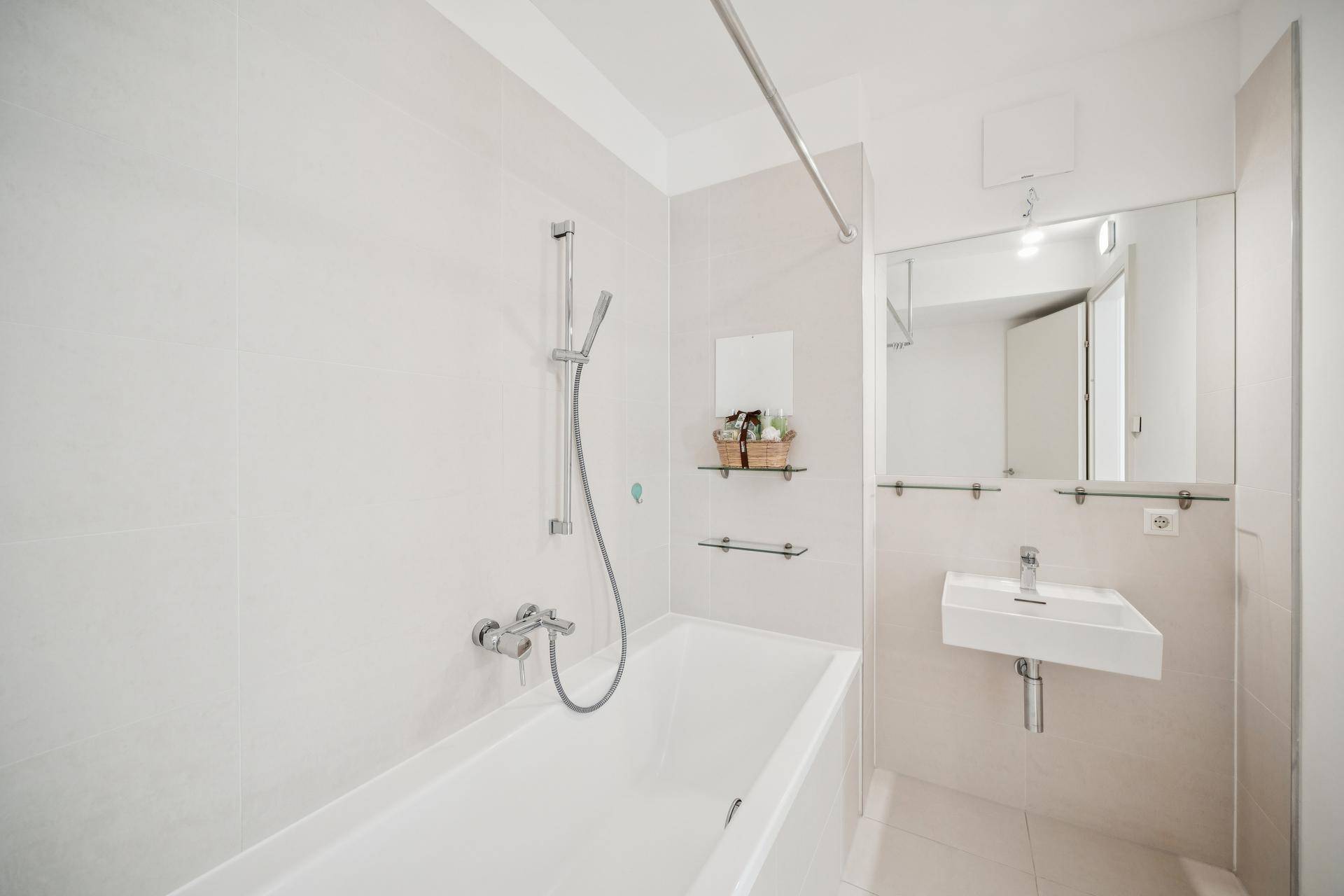 Helles Badezimmer mit Badewanne, Waschbecken und großem Spiegel.