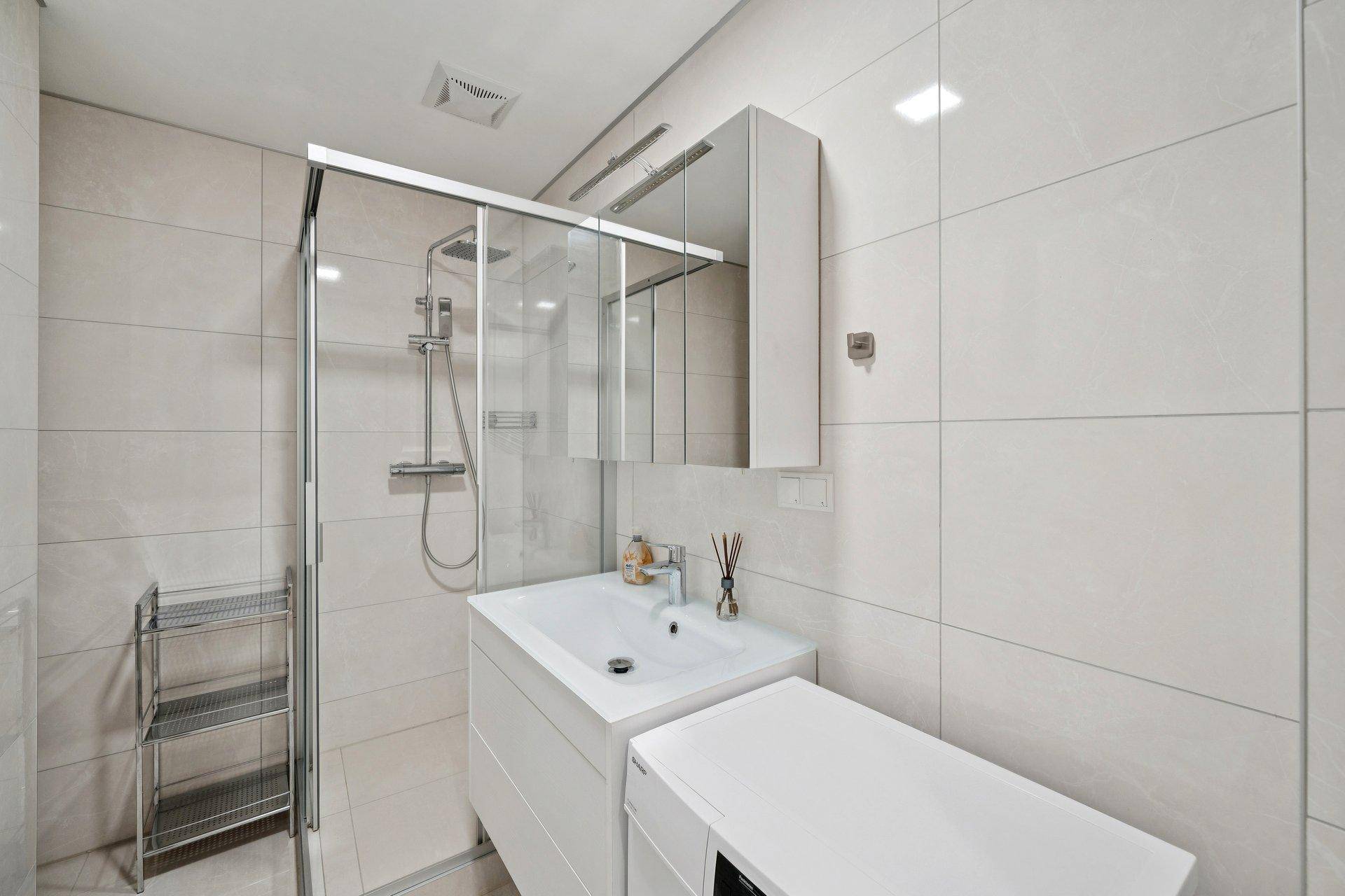 Modernes Badezimmer mit Dusche, Einzelwaschbecken und Waschmaschine.