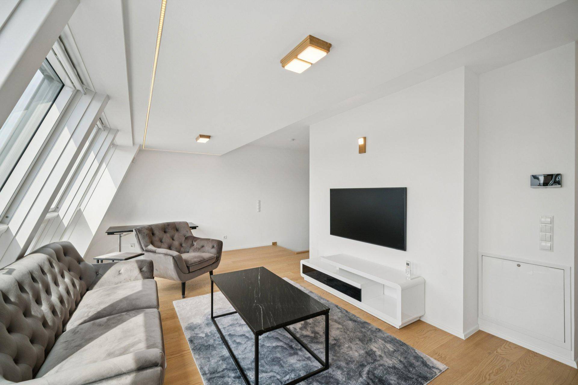 Modern eingerichtetes Wohnzimmer mit bequemen Sofas, Holzboden und einem Flachbildfernseher.