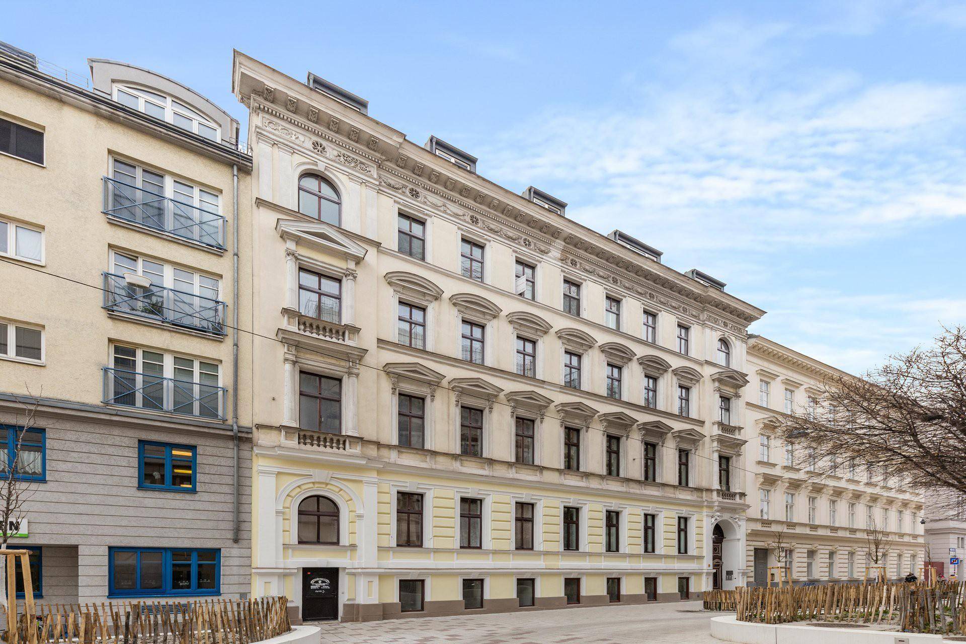 Historische Fassade eines eleganten Altbaus mit vielen Fenstern und klassischer Architektur.