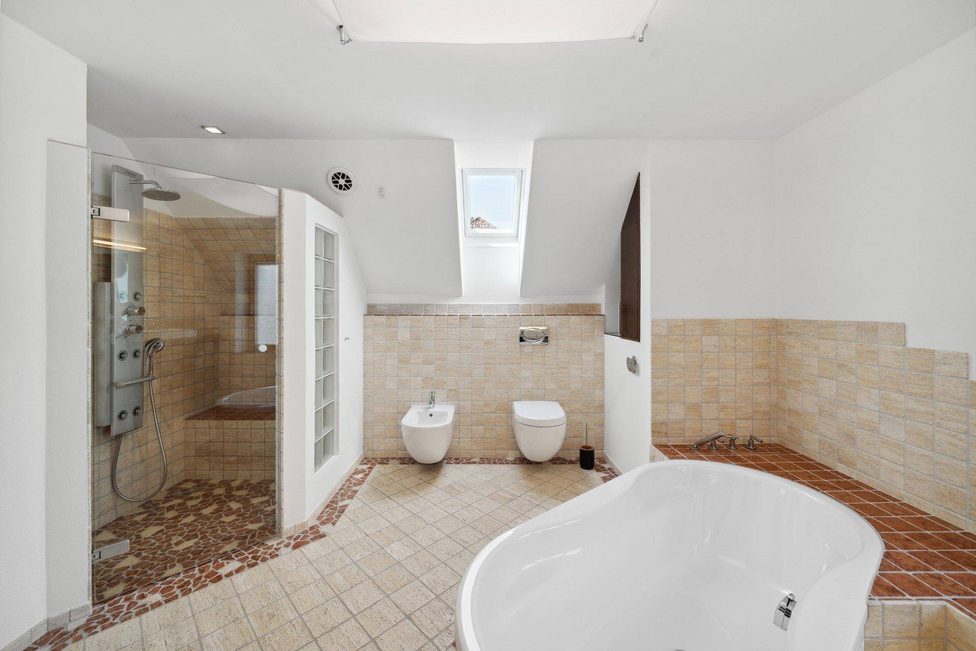 Geräumiges Badezimmer mit freistehender Badewanne, Dusche, Bidet und Dachfenster.
