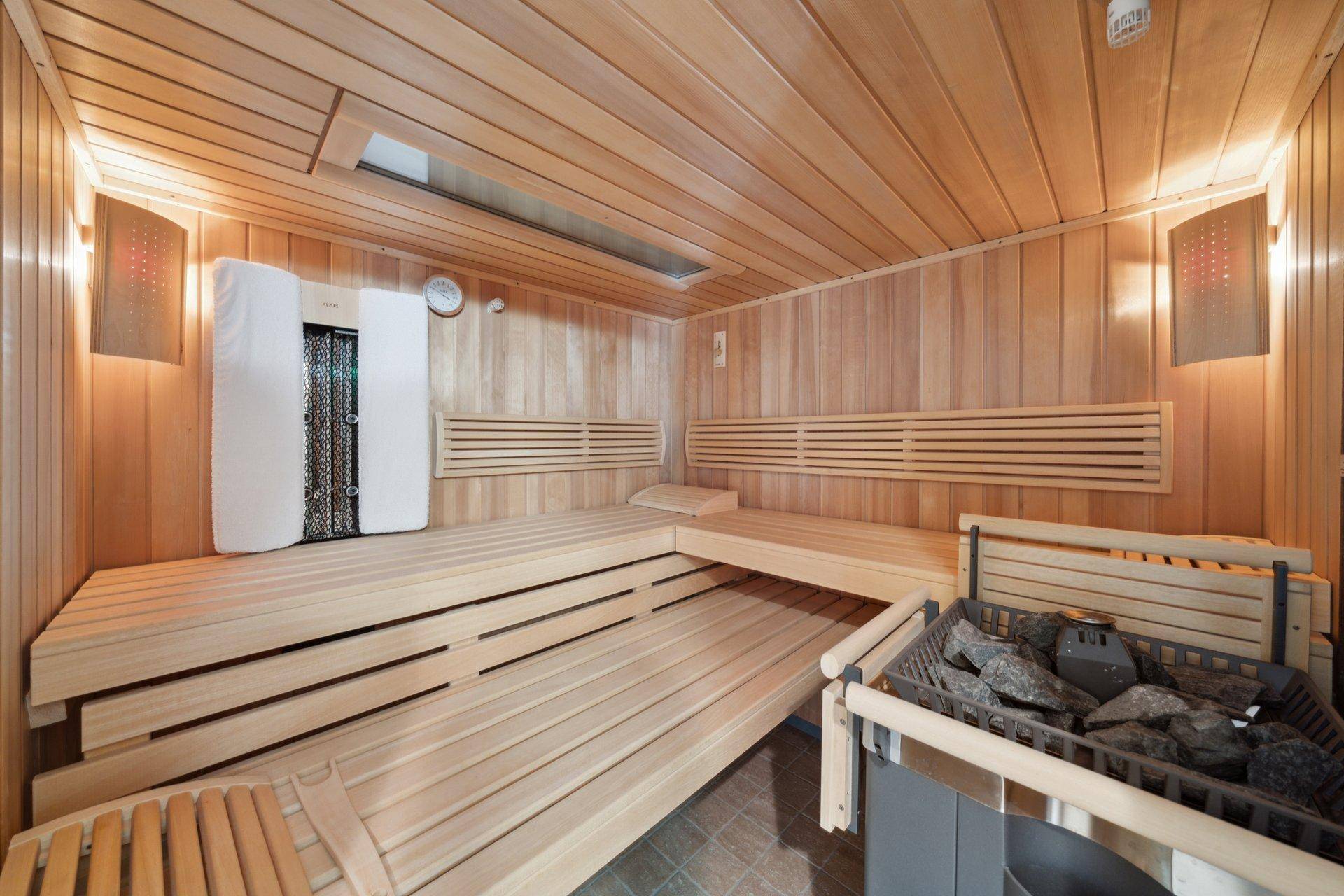 Holzvertäfelte Sauna mit mehreren Bänken und einem traditionellen Saunaofen.