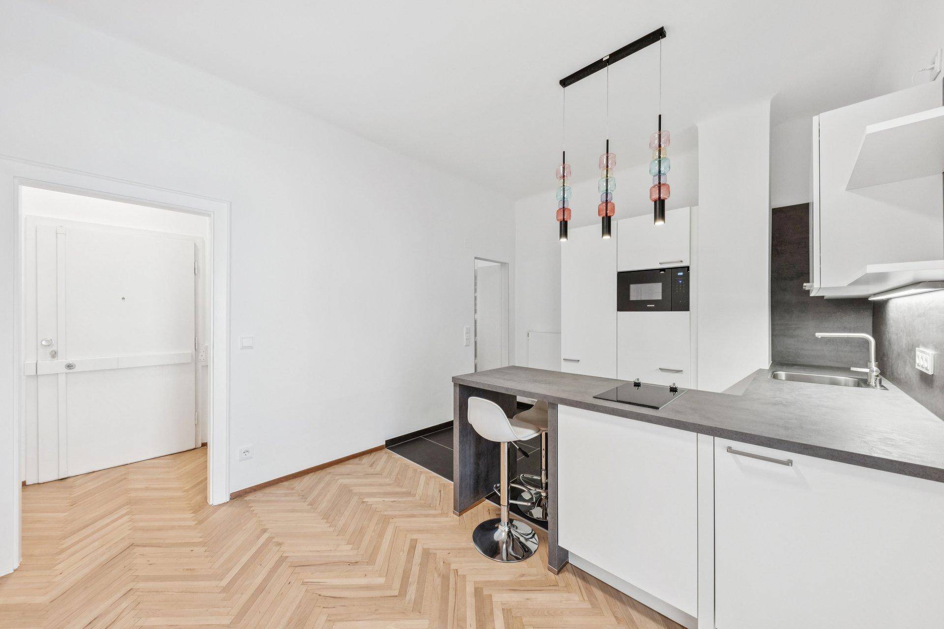 Moderne Küchenzeile mit Bartresen, Induktionskochfeld und integrierten Geräten.