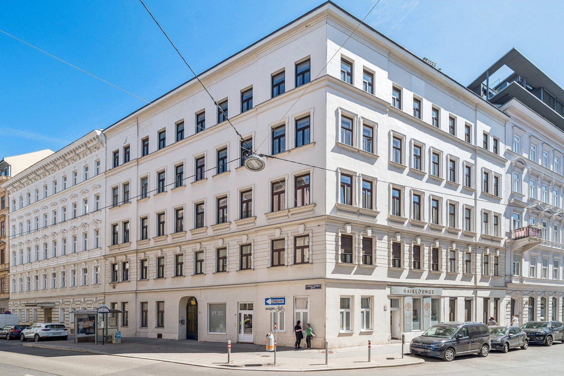 Elegantes Eckgebäude mit klassischer Architektur und vielen Fenstern in urbaner Umgebung.