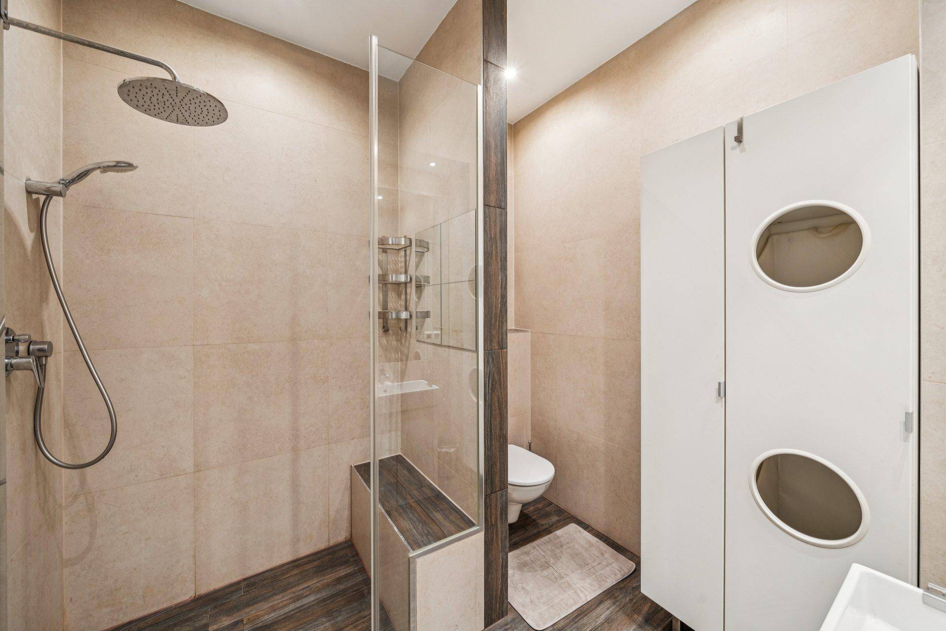 Kompaktes Badezimmer mit Dusche, Toilette und Waschbecken, ausgestattet mit hellen Fliesen.