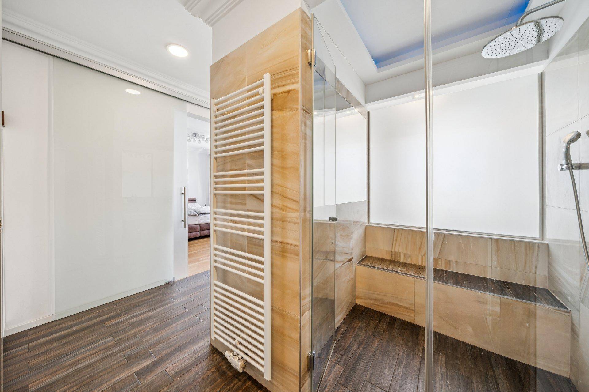 Modernes Badezimmer mit begehbarer Dusche, Regendusche und beheiztem Handtuchhalter.