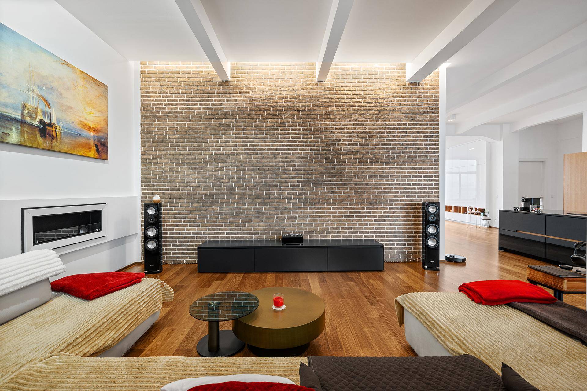 Wohnzimmer mit Ziegelwand, integriertem Kamin und Holzboden, umgeben von bequemen Sofas.
