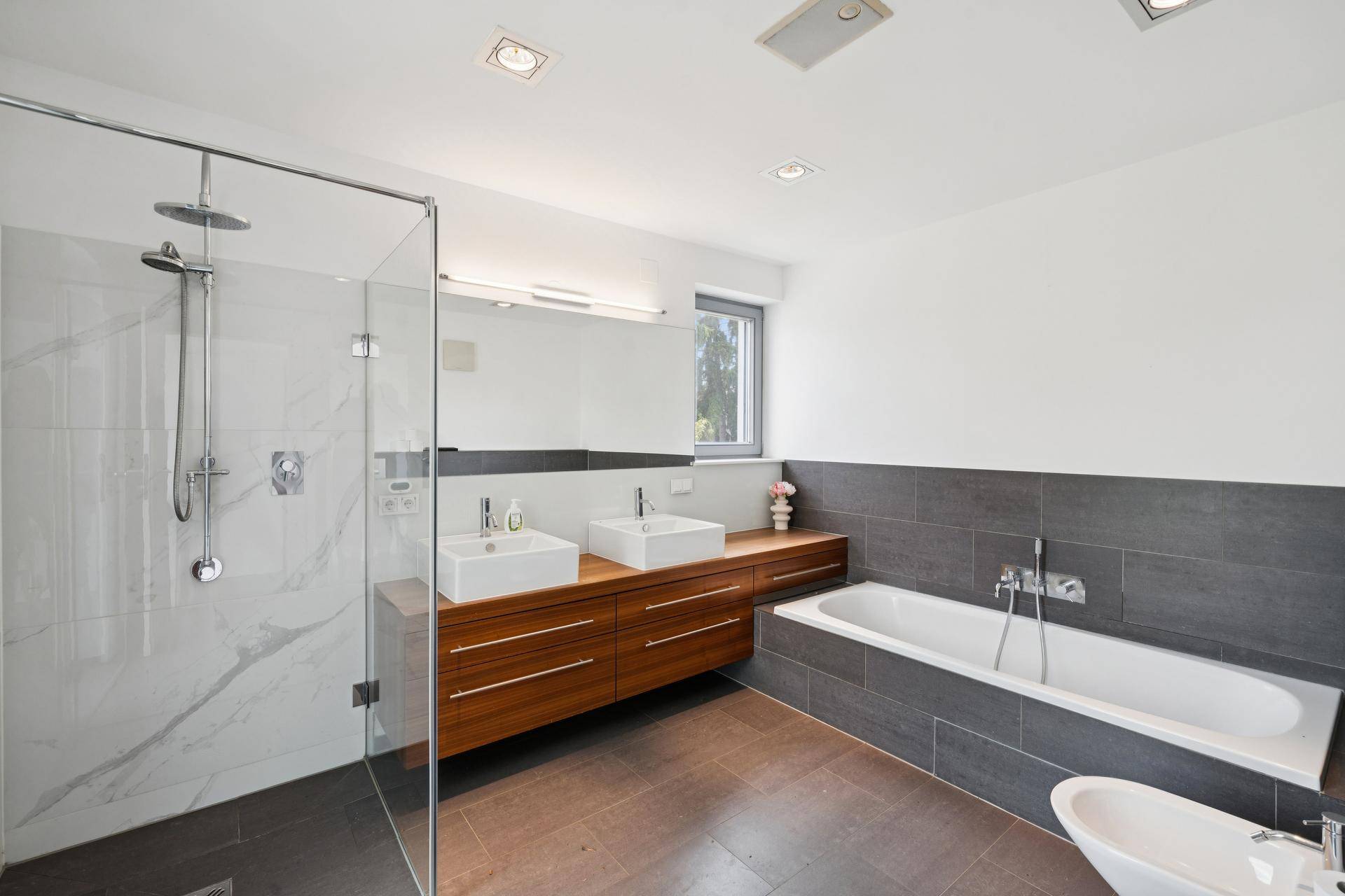 Modernes Badezimmer mit begehbarer Dusche, Doppelwaschbecken, Badewanne und Fenster.