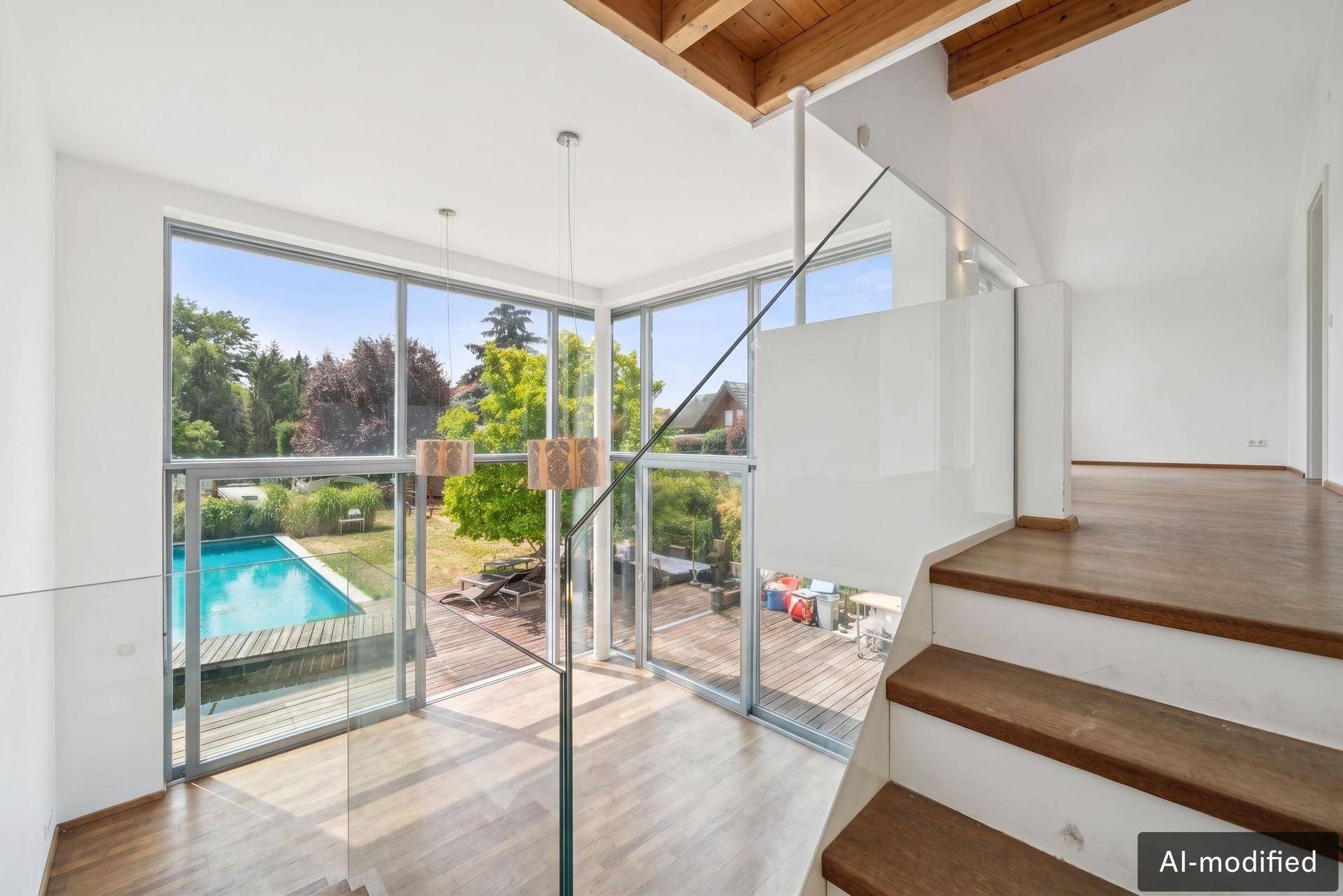 Lichtdurchfluteter Treppenbereich mit Blick auf den Garten und Pool durch raumhohe Fenster.