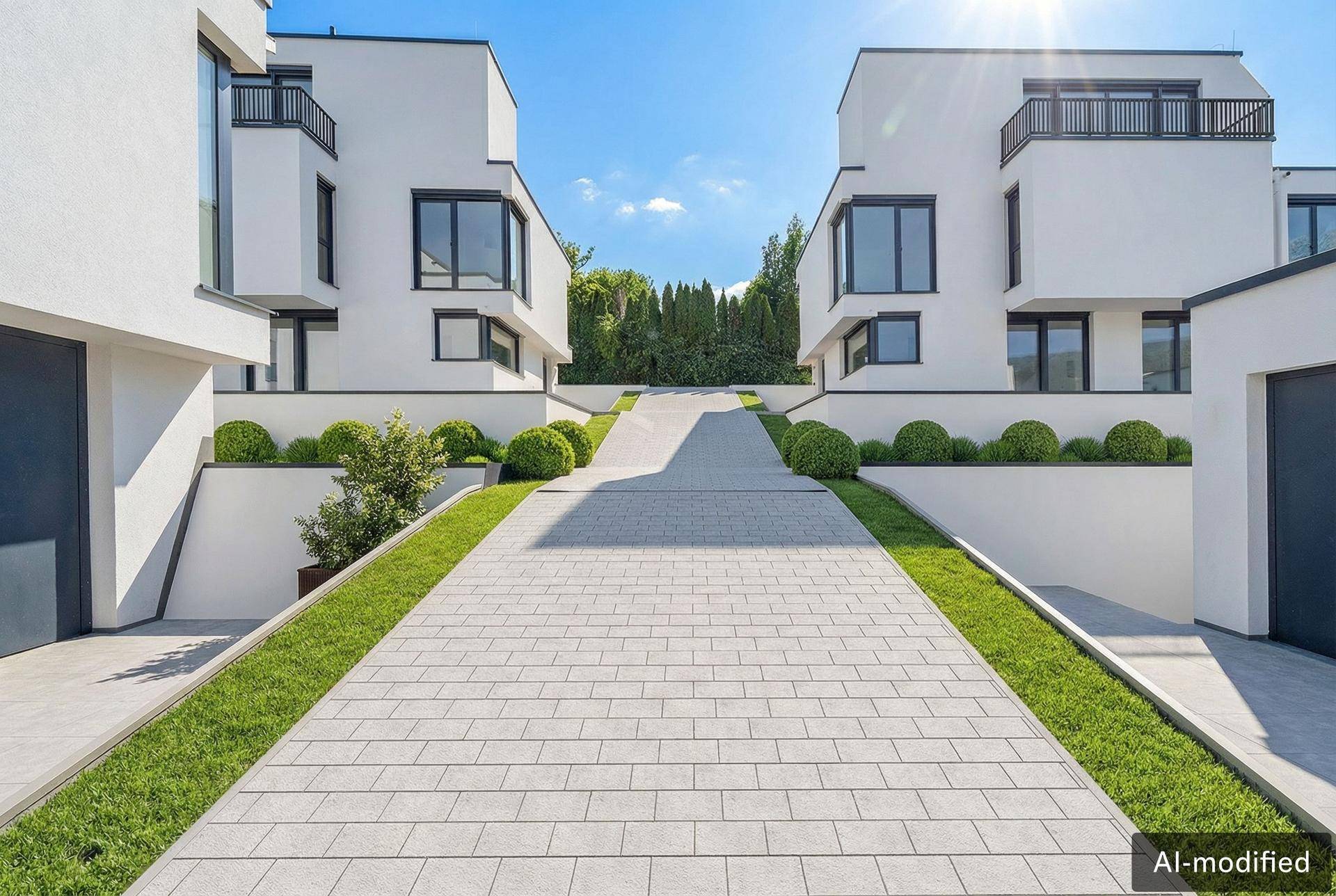 Moderne Doppelhaushälften mit gepflasterter Zufahrt und gepflegter Grünanlage.