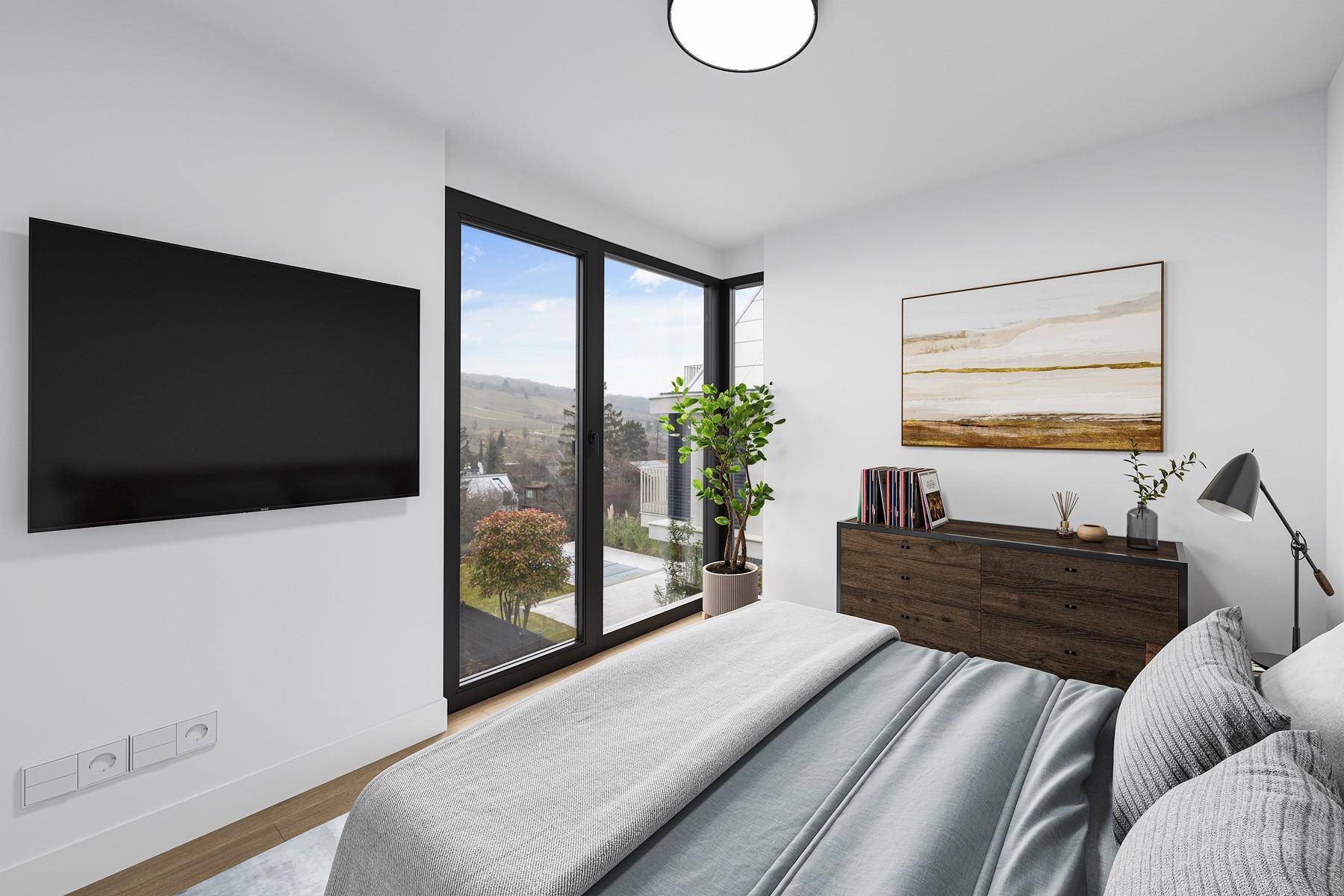 Helles Schlafzimmer mit großen Fenstern, die einen weiten Blick ins Grüne bieten, und modernem Mobiliar.