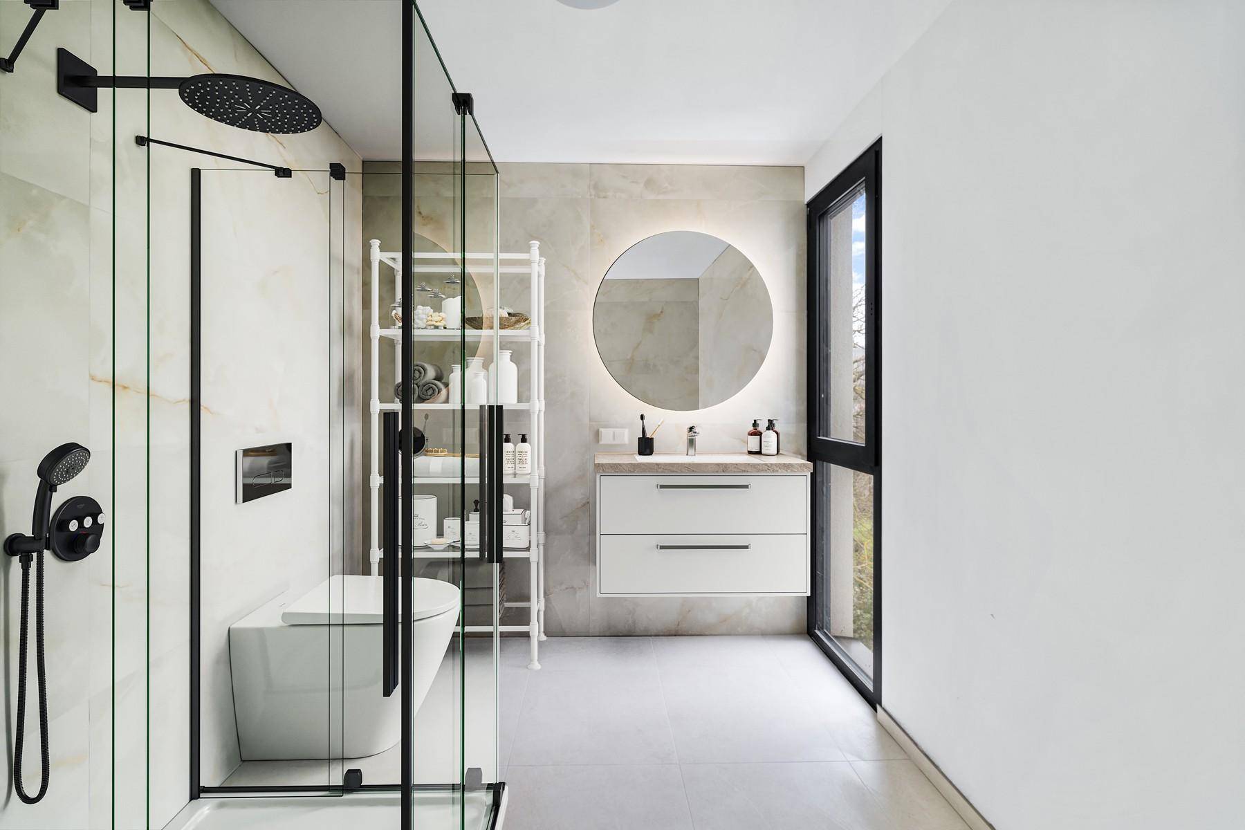 Modernes Badezimmer mit begehbarer Dusche, eleganten Fliesen und einem runden, beleuchteten Spiegel über dem Waschtisch.