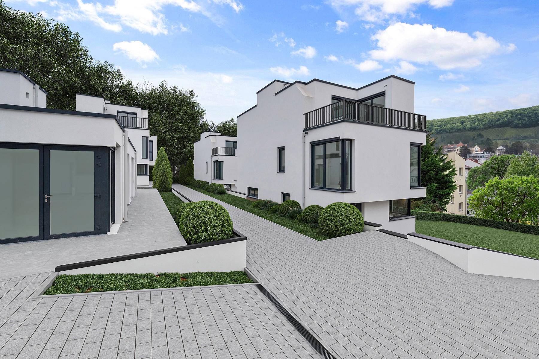 Architektonisch ansprechende weiße Villen mit Flachdächern und Balkonen, umgeben von grüner Landschaft und gepflasterten Wegen.