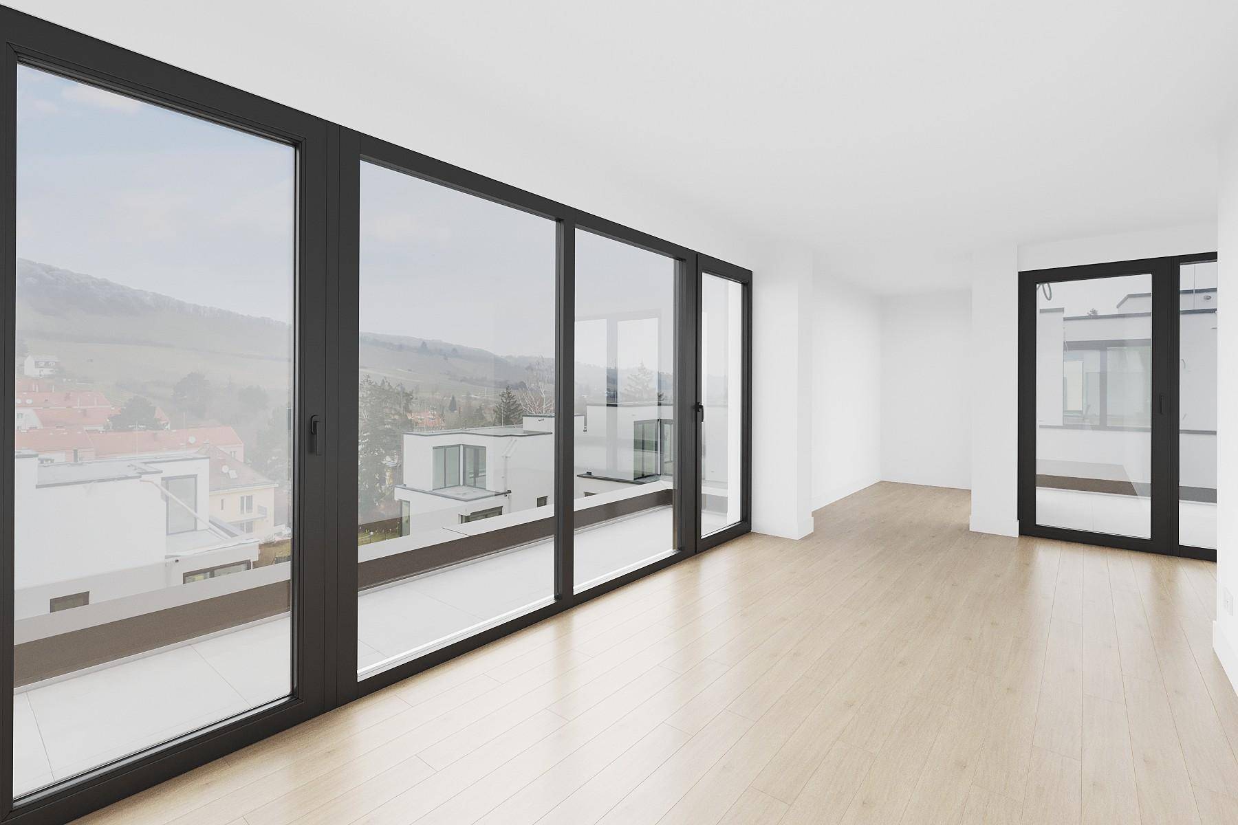 Geräumiger, heller Raum mit großen Glasfronten und Zugang zu einer Terrasse.