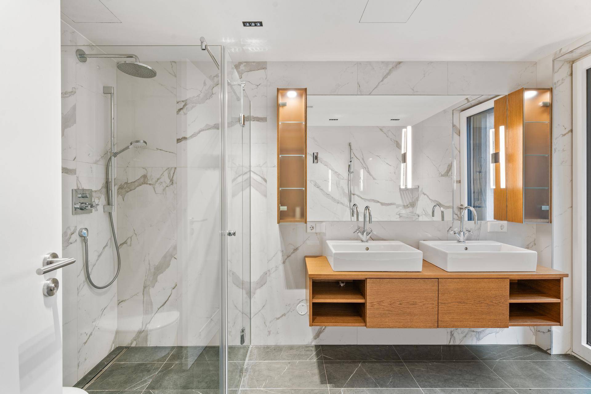 Modernes Badezimmer mit begehbarer Dusche, Doppelwaschbecken und eleganten Marmorfliesen.