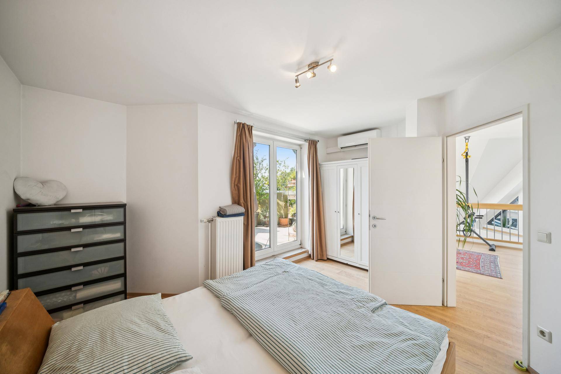 Schlafzimmer mit Holzboden, Klimaanlage und Zugang zu einem Außenbereich.