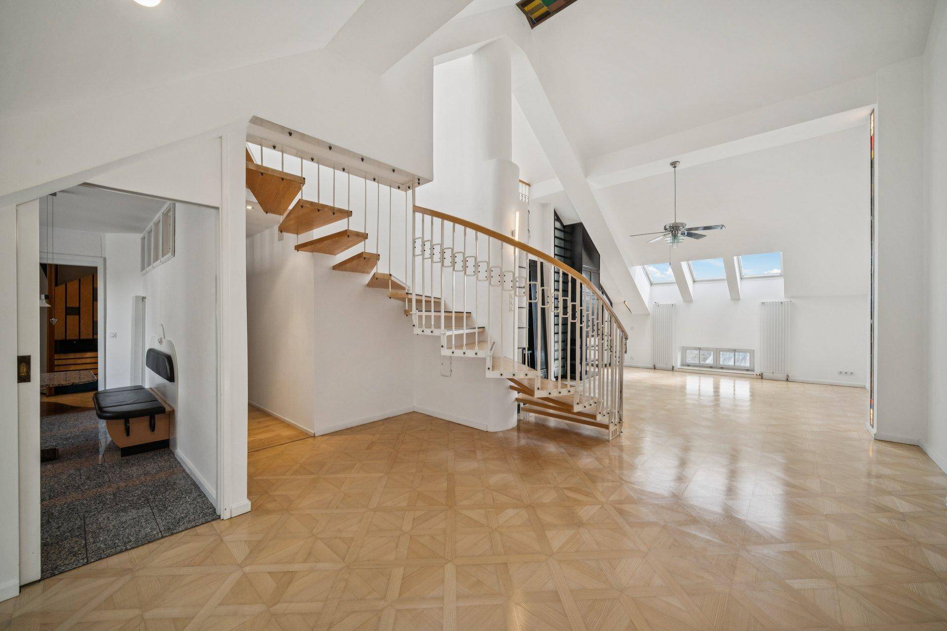 Heller Flurbereich mit eleganter Wendeltreppe, Parkettboden und hohen Decken.