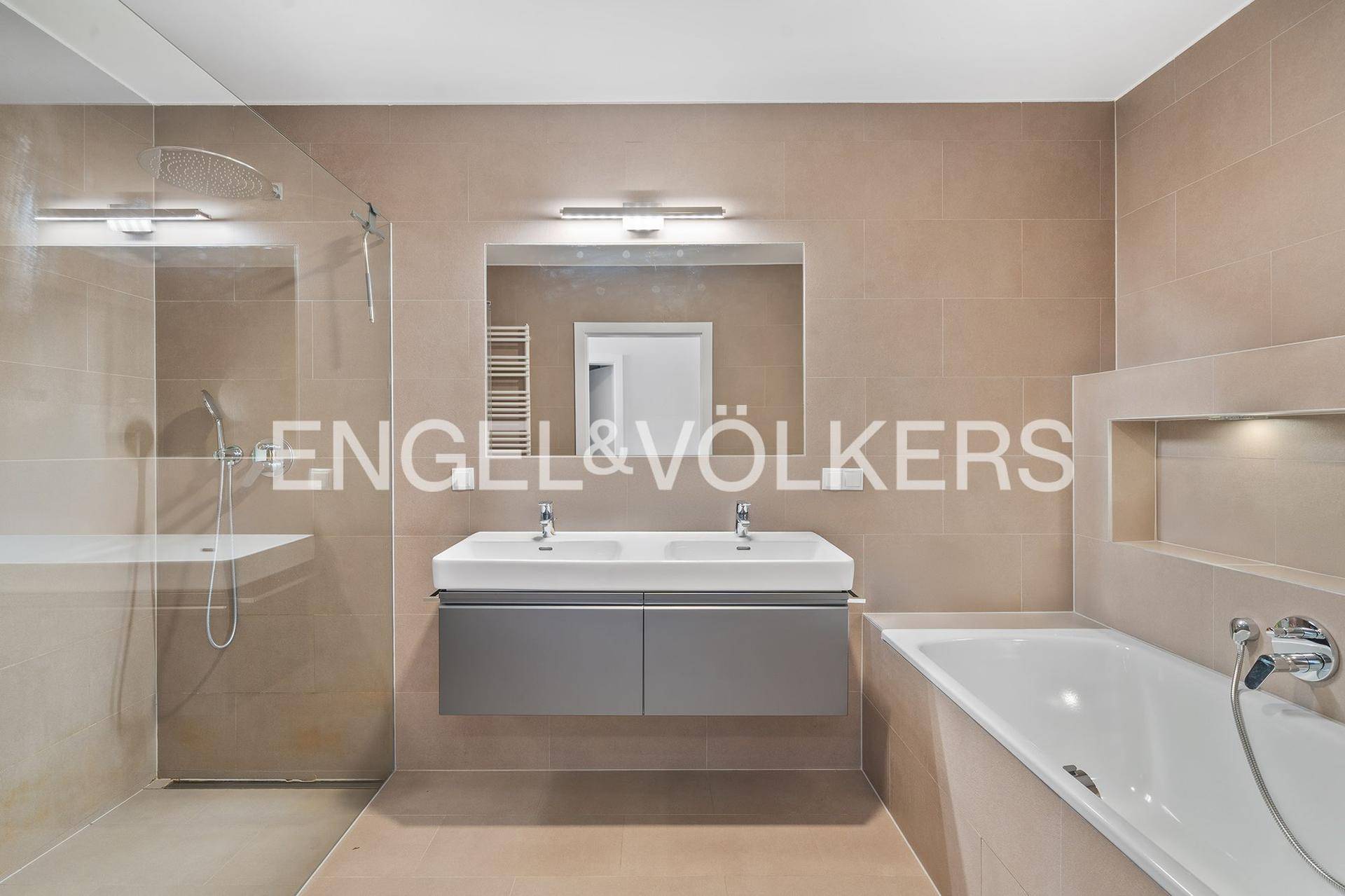 Modernes Badezimmer mit Doppelwaschbecken, begehbarer Dusche, Badewanne und beigefarbenen Fliesen.