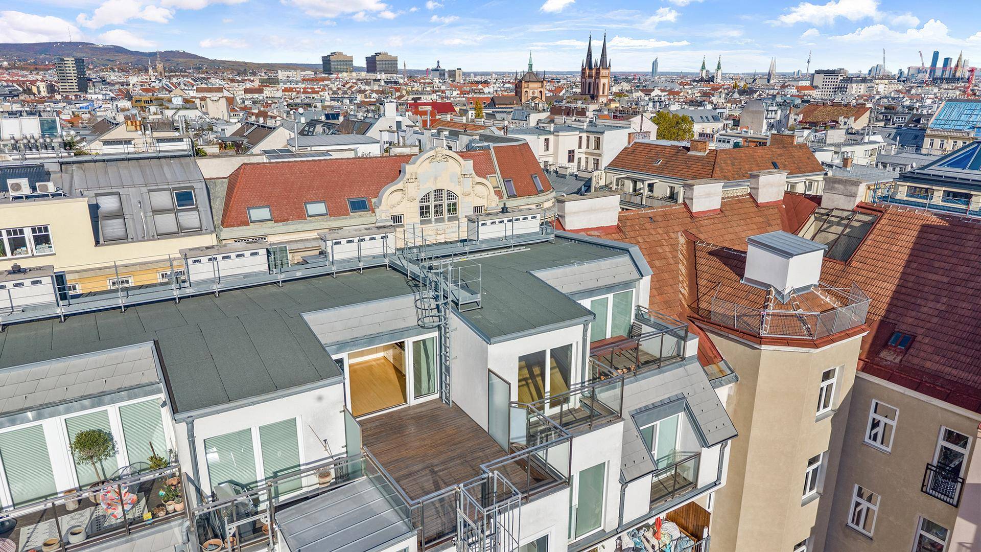 Luftaufnahme eines modernen Gebäudes mit Dachterrassen und Blick über die Stadt.
