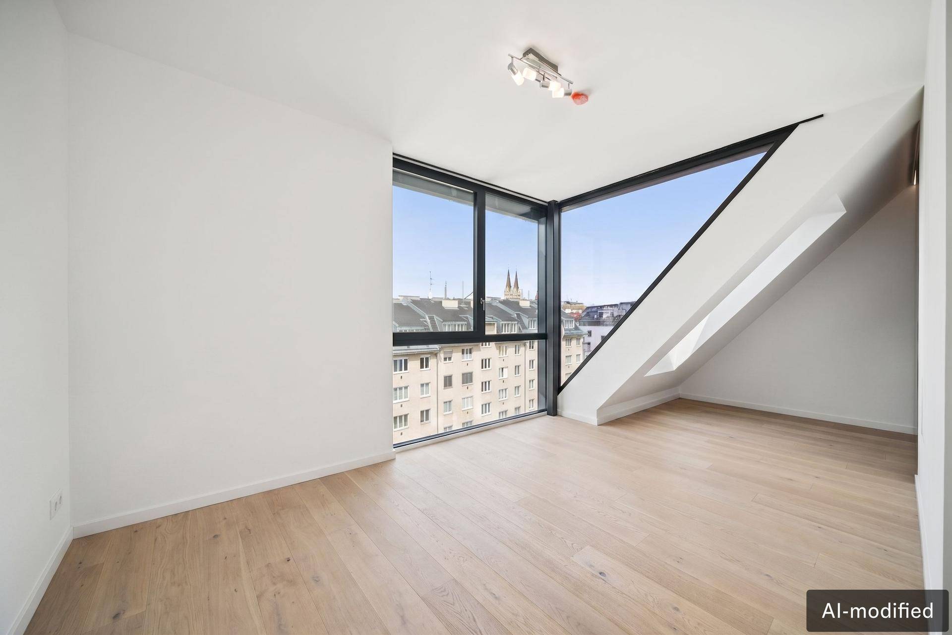 Lichtdurchflutetes Zimmer mit schrägen Fenstern und weitem Blick über die Stadt.