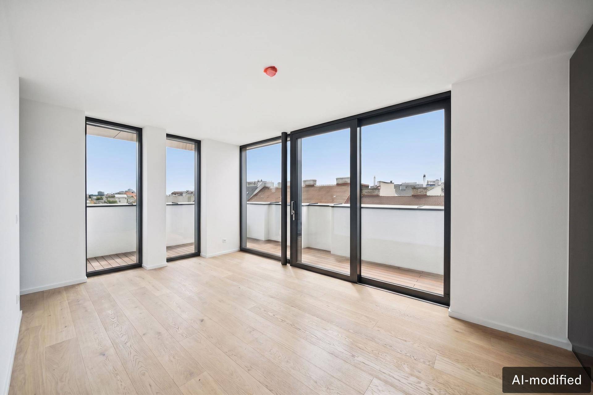 Helles, leeres Zimmer mit Holzboden und Zugang zu einem Balkon mit Stadtblick.