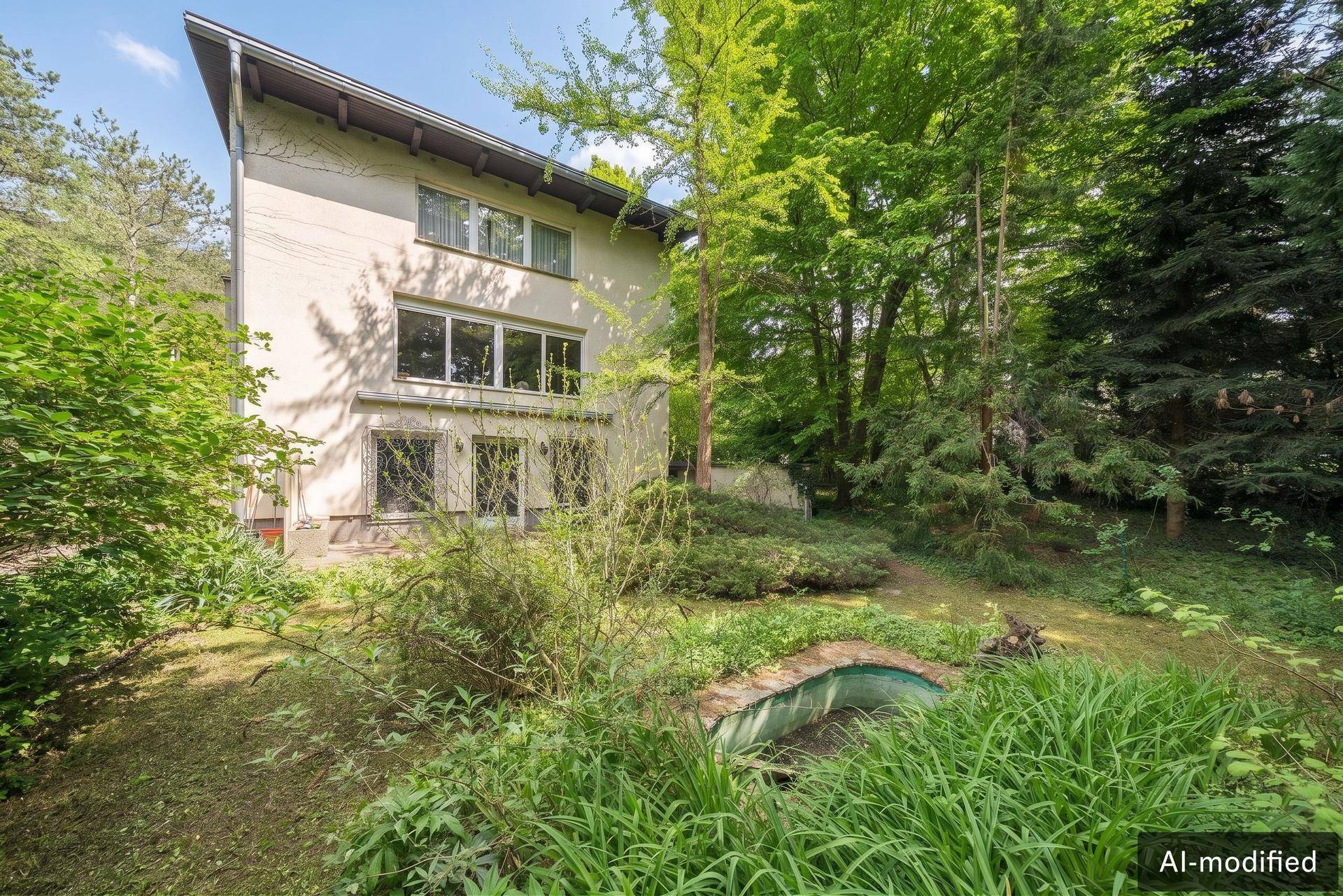 Rückansicht des Hauses mit großen Fenstern, umgeben von einem weitläufigen, grünen Gartenbereich.