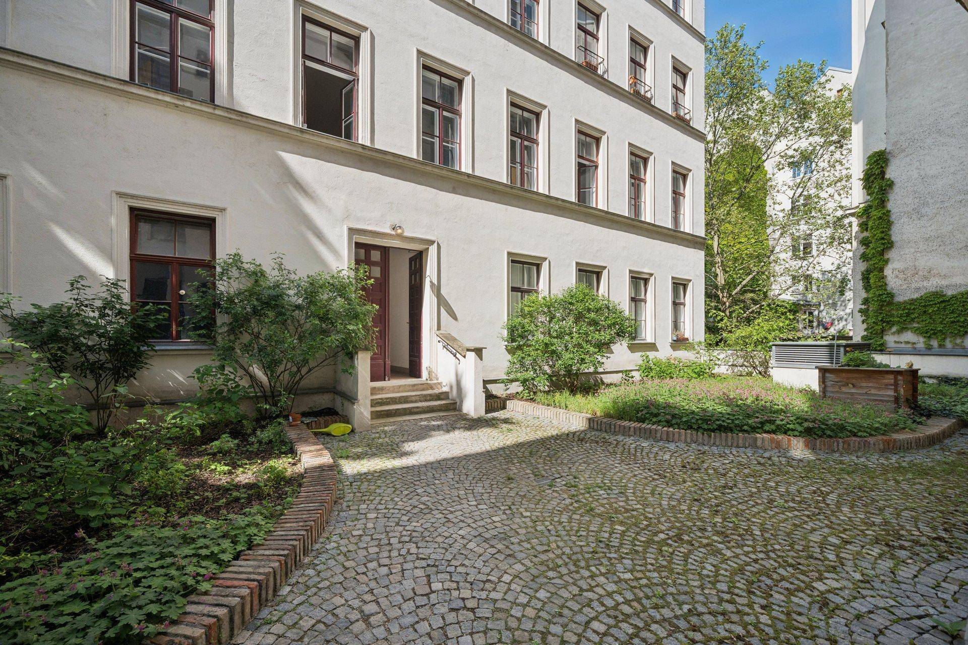 Ruhiger Innenhof mit Kopfsteinpflaster und grünen Büschen, bietet einen privaten Rückzugsort.