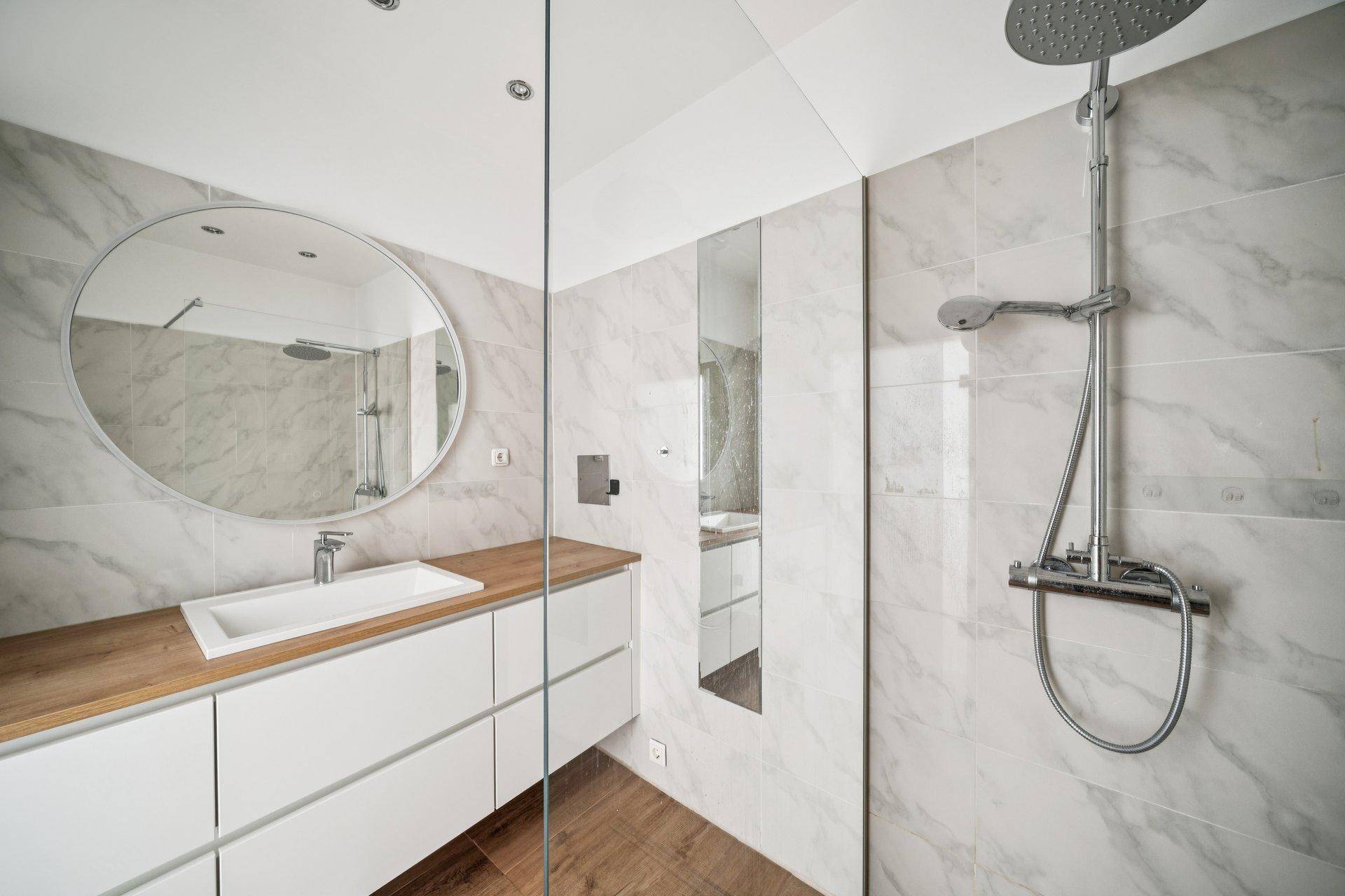 Modernes Badezimmer mit großer Dusche, Marmorfliesen und Holzwaschtisch.