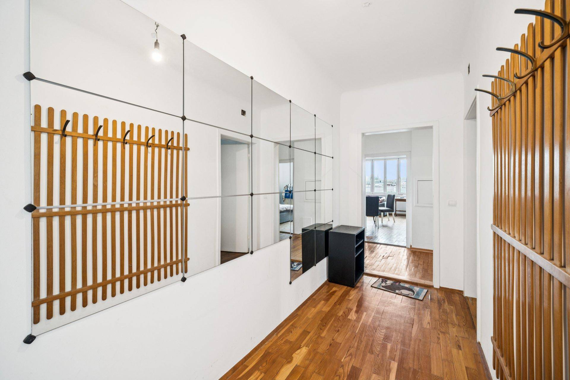 Heller Flur mit Holzboden, großen Spiegeln und Garderobe.