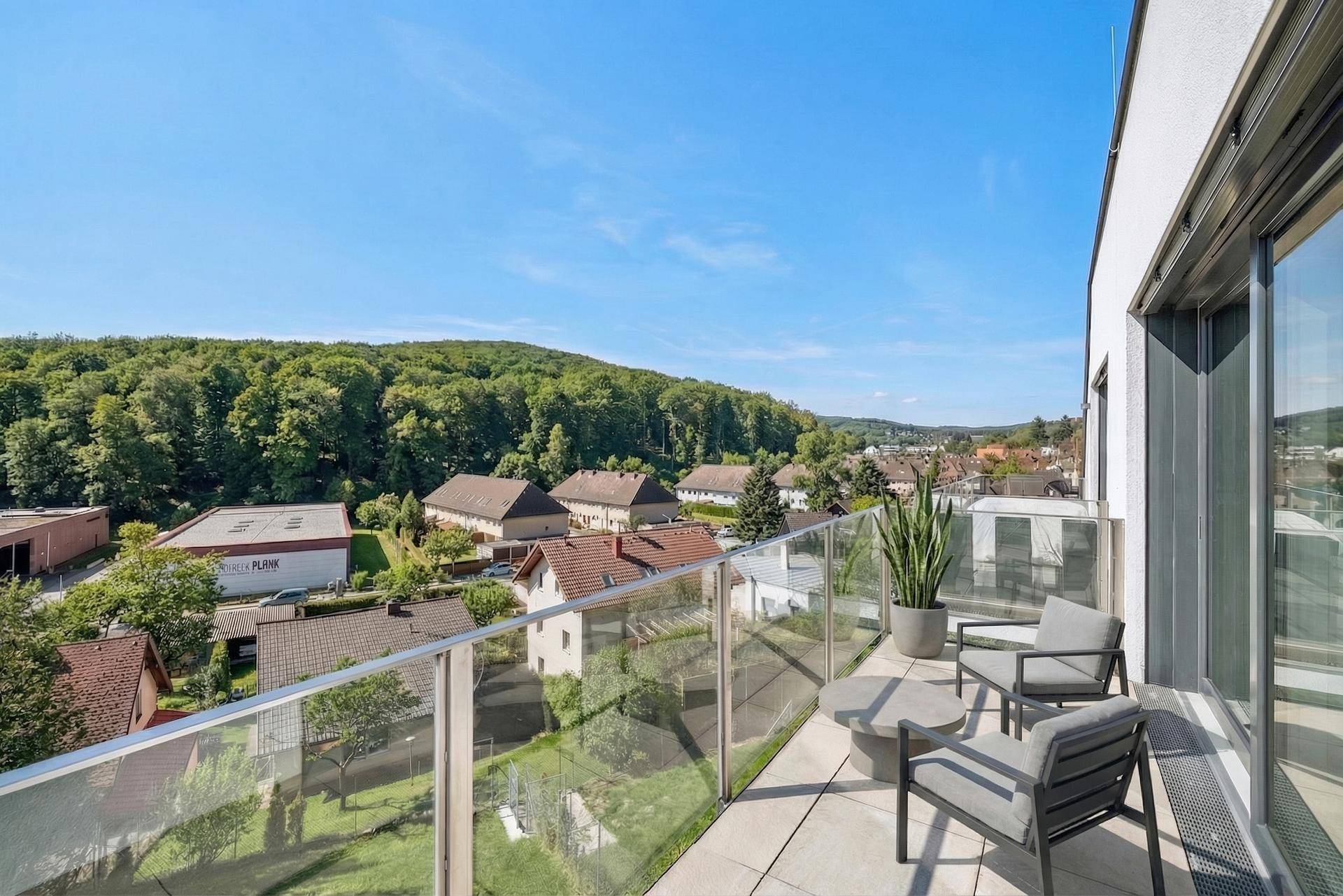 Geräumiger Balkon mit Glasgeländer und Sitzgelegenheiten, bietet eine weite Aussicht.