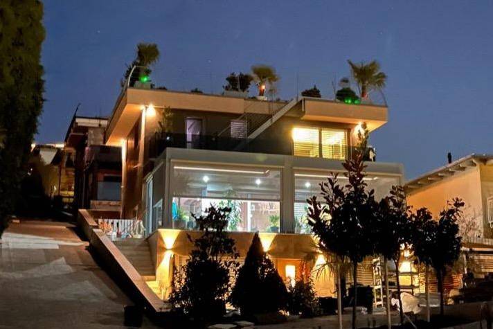 Beleuchtete moderne Villa bei Nacht mit stimmungsvoller Außenbeleuchtung und Pflanzen.