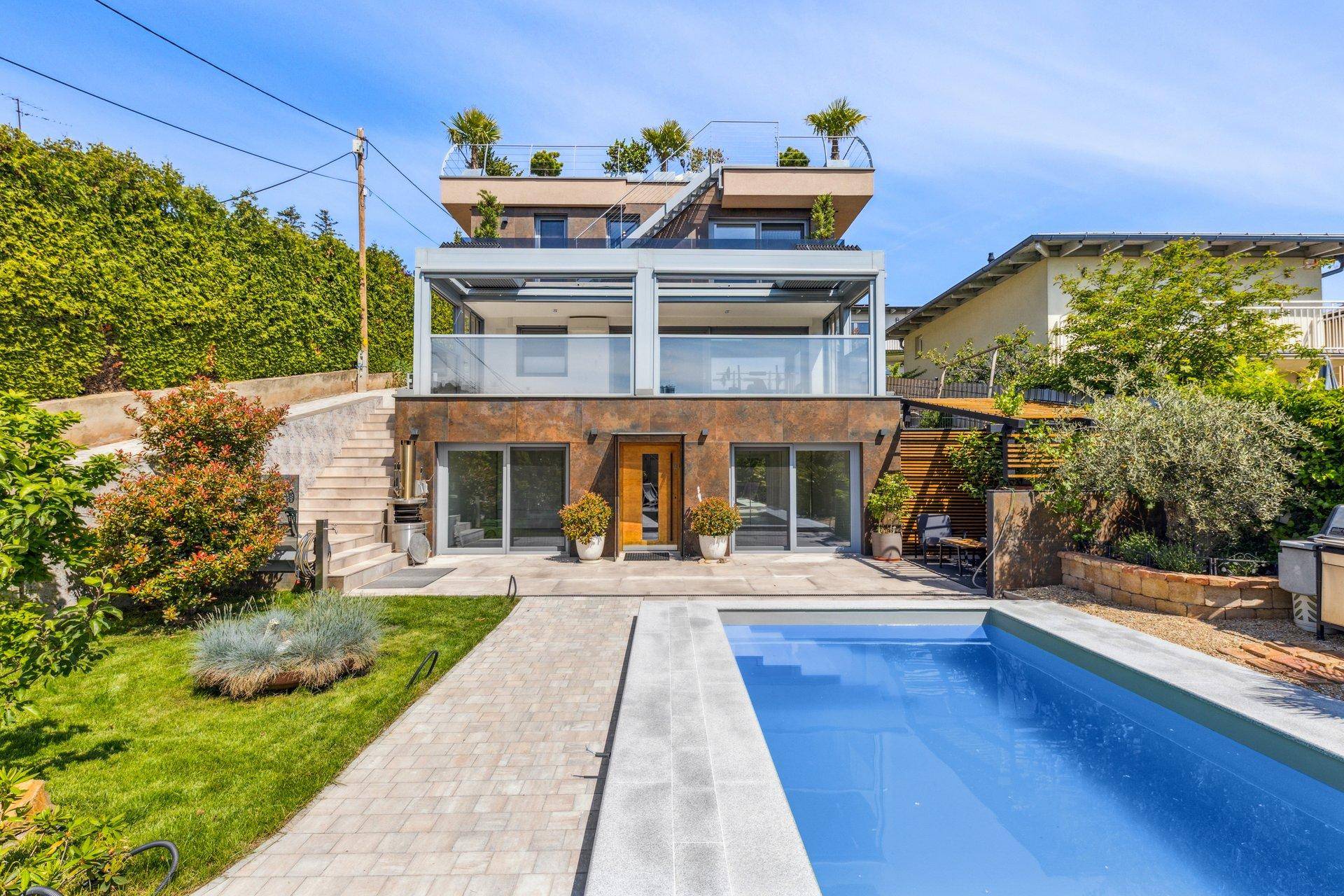 Moderne Villa mit mehreren Terrassen, großem Pool und gepflegtem Gartenbereich.