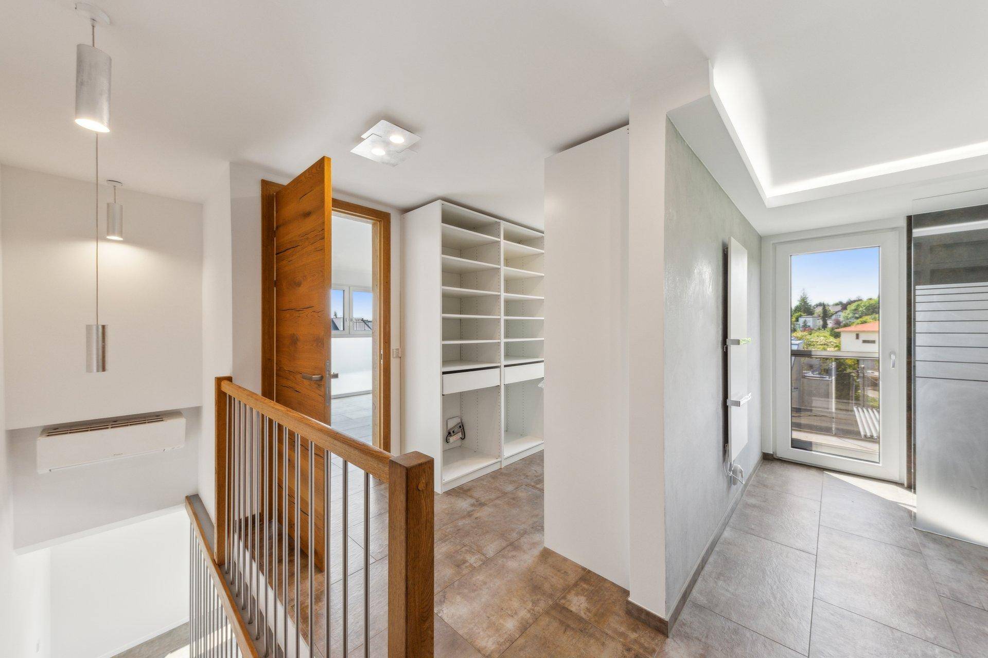 Heller Flur mit integriertem begehbarem Kleiderschrank und Zugang zu einem Balkon.