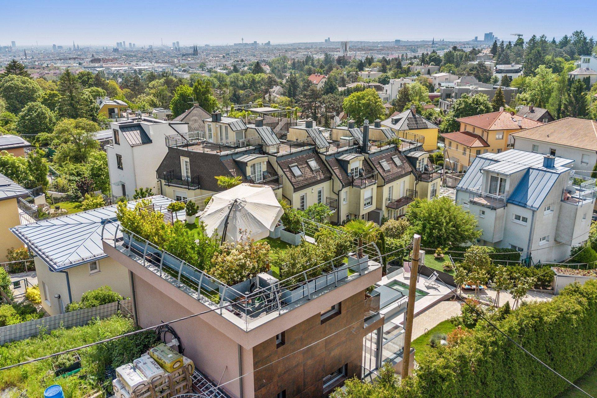 Panoramablick auf die moderne Villa mit Dachterrasse und die umliegende Stadtlandschaft.