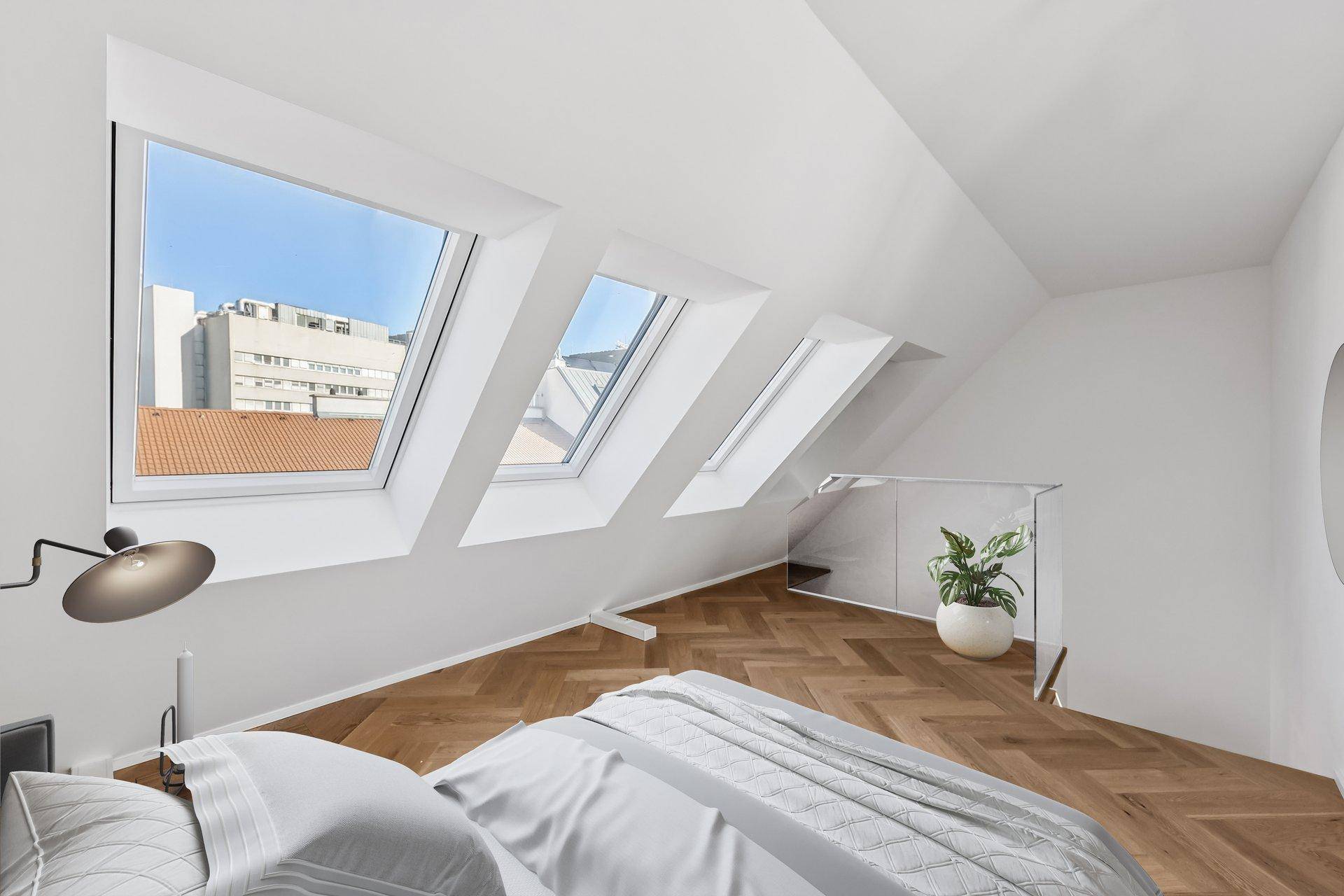 Helles Schlafzimmer im Dachgeschoss mit schrägen Wänden und großen Dachfenstern.