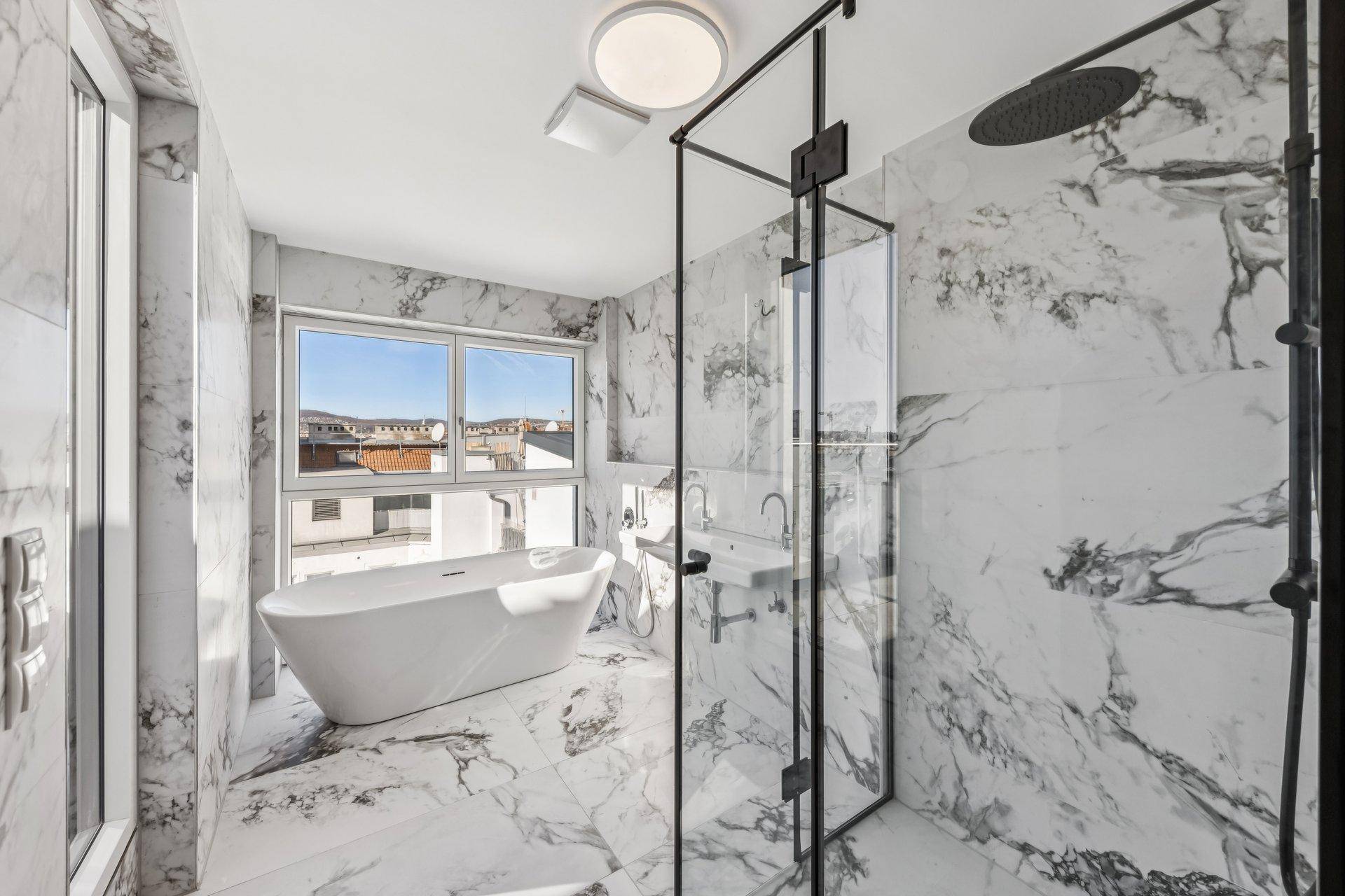 Luxuriöses Badezimmer mit Marmorfliesen, freistehender Badewanne und großer Dusche.