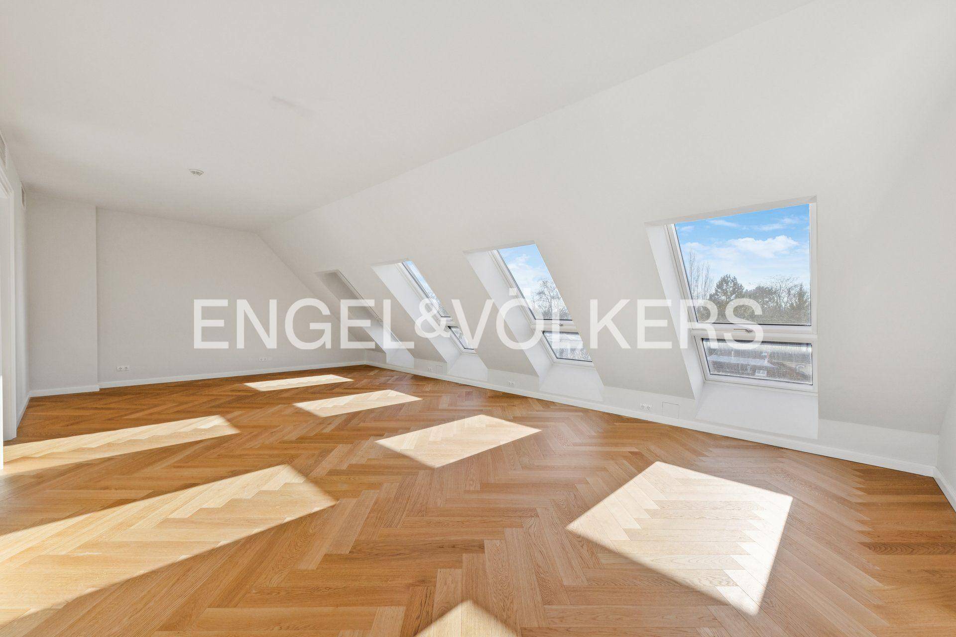 Heller Dachbodenraum mit schrägen Decken, mehreren Dachfenstern und Fischgrätparkett.