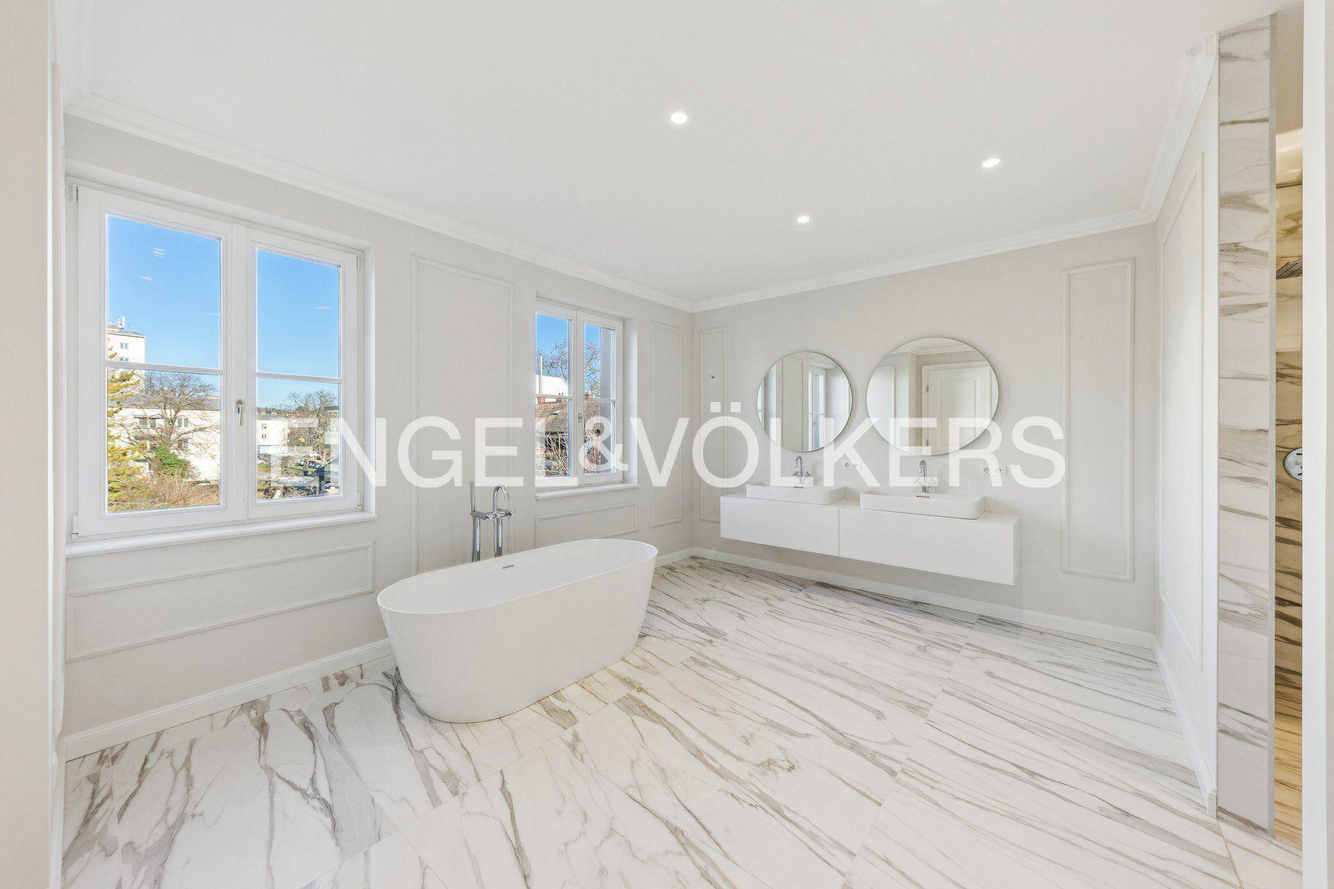 Luxuriöses Badezimmer mit freistehender Badewanne, Doppelwaschbecken und Marmoroberflächen.