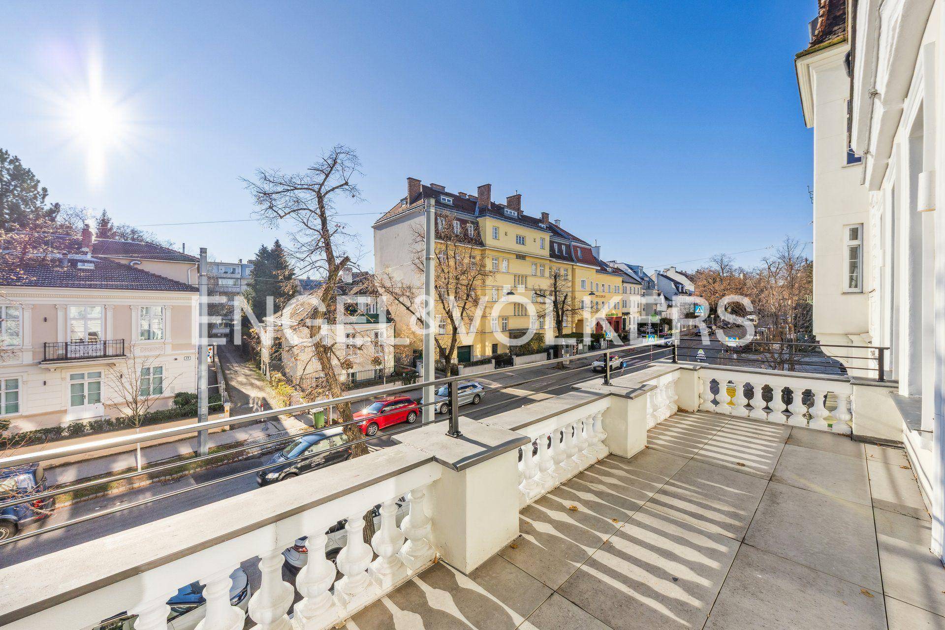 Geräumige Sonnenterrasse mit klassischer Balustrade und Blick auf die belebte Straße.
