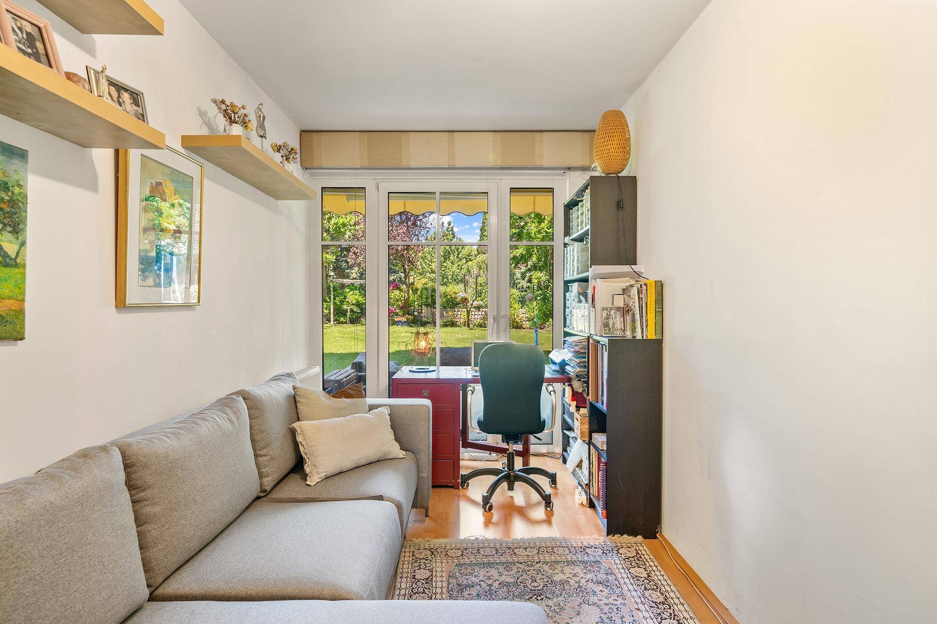 Gemütliches Arbeitszimmer mit Sofa, Schreibtisch und direktem Zugang zum grünen Gartenbereich.