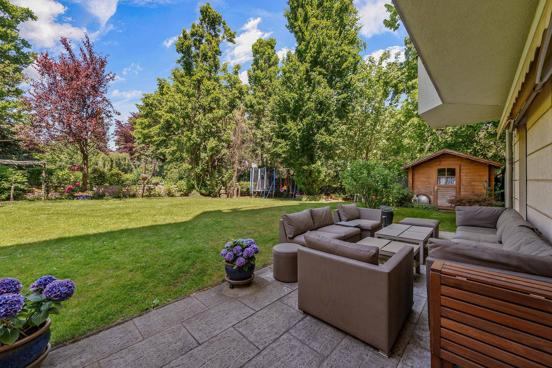 Geräumige Terrasse mit bequemen Loungemöbeln, Steinplattenboden und Blick auf den großen Garten.