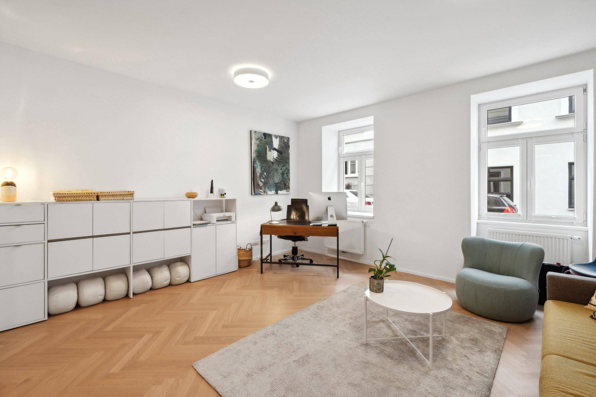 Geräumiges Wohnzimmer mit Arbeitsbereich, Stauraum und Fischgrätparkett.