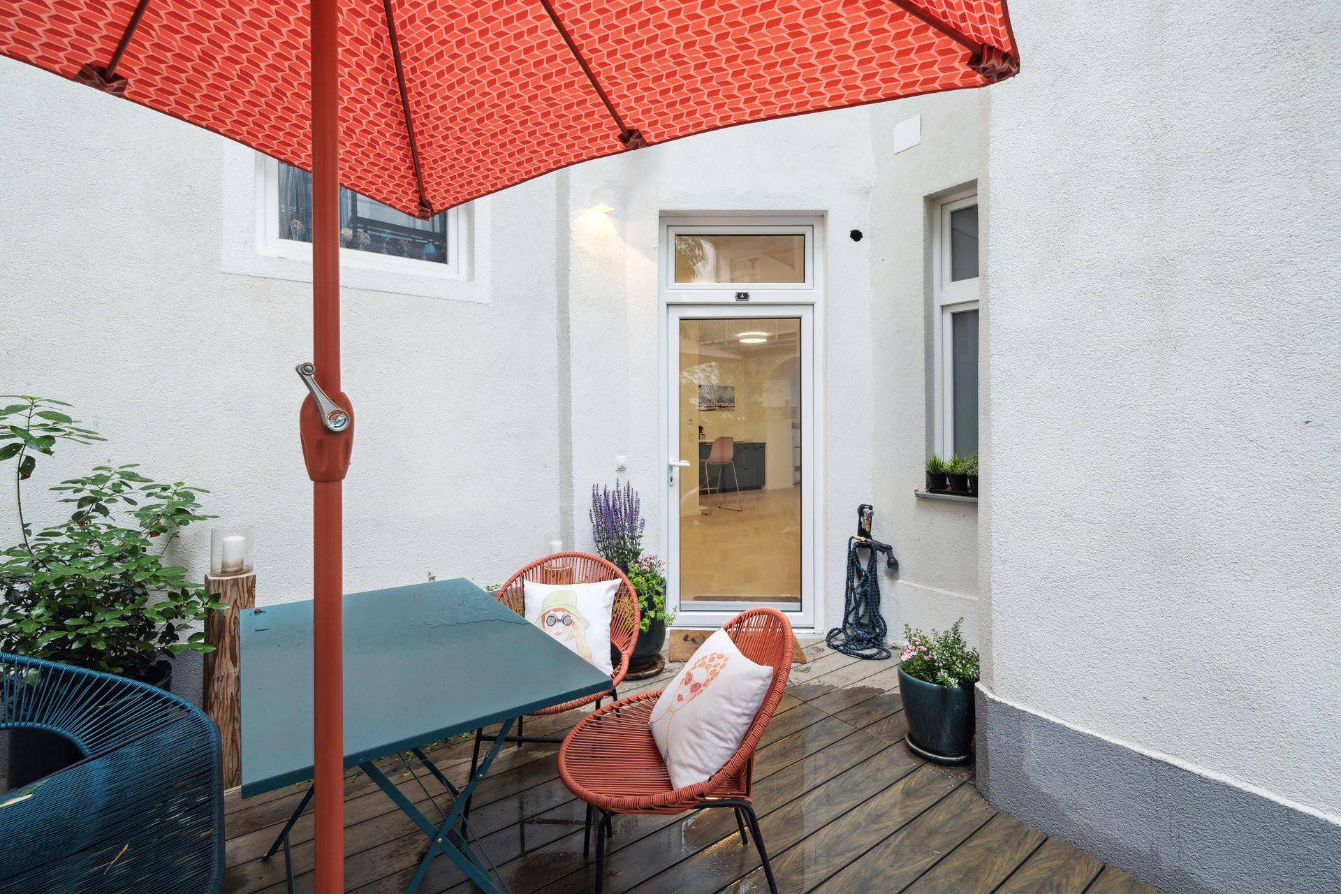 Terrasse mit direktem Zugang zum Innenbereich und schützendem Sonnenschirm.