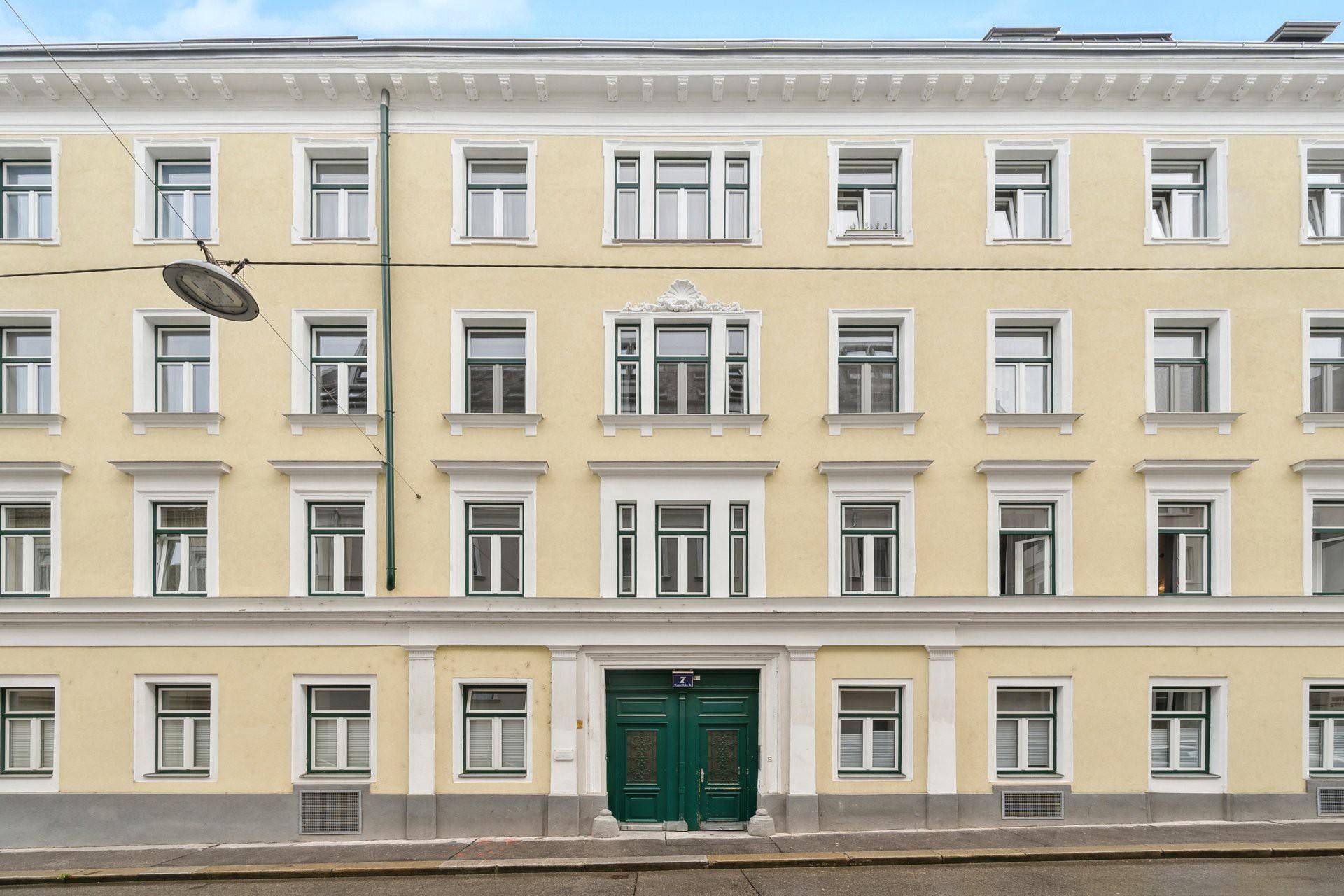 Historische Fassade eines Wiener Altbaus mit vielen Fenstern und grüner Eingangstür.